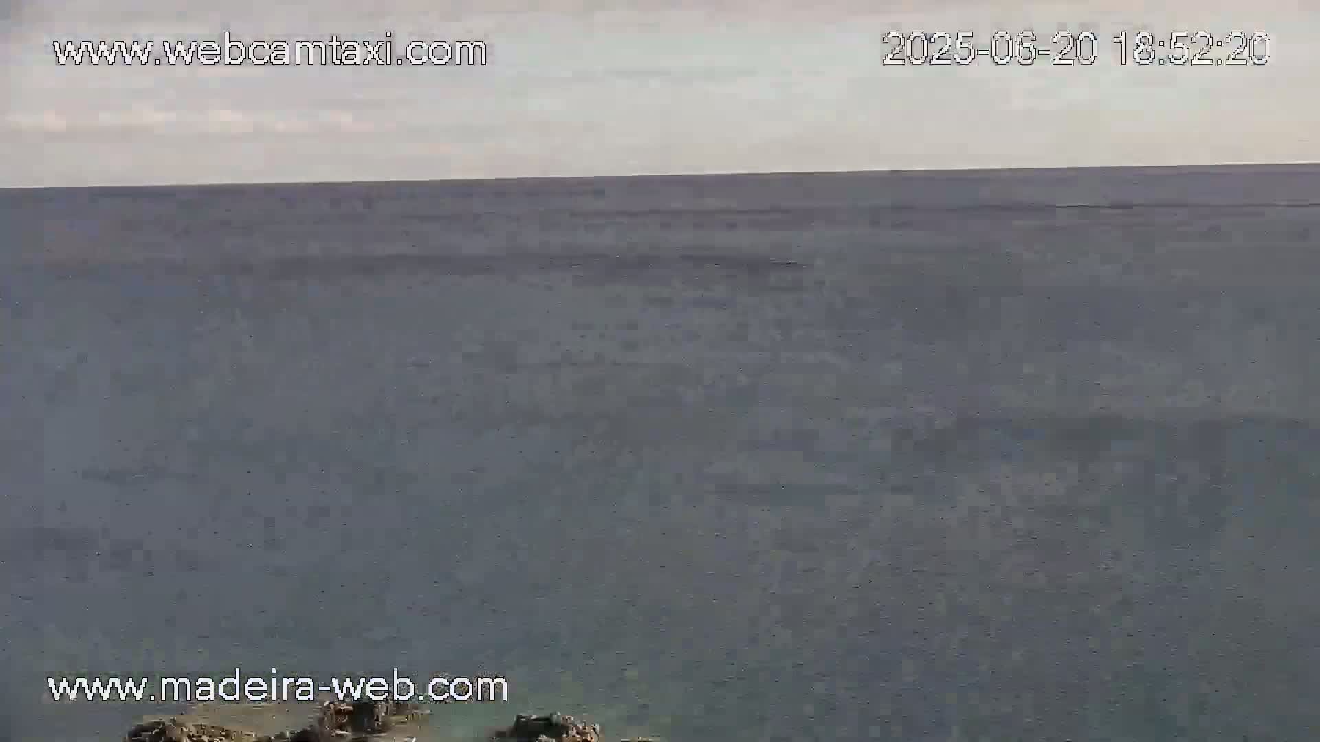 A wide expanse of calm, gray-blue ocean is seen under an overcast sky.