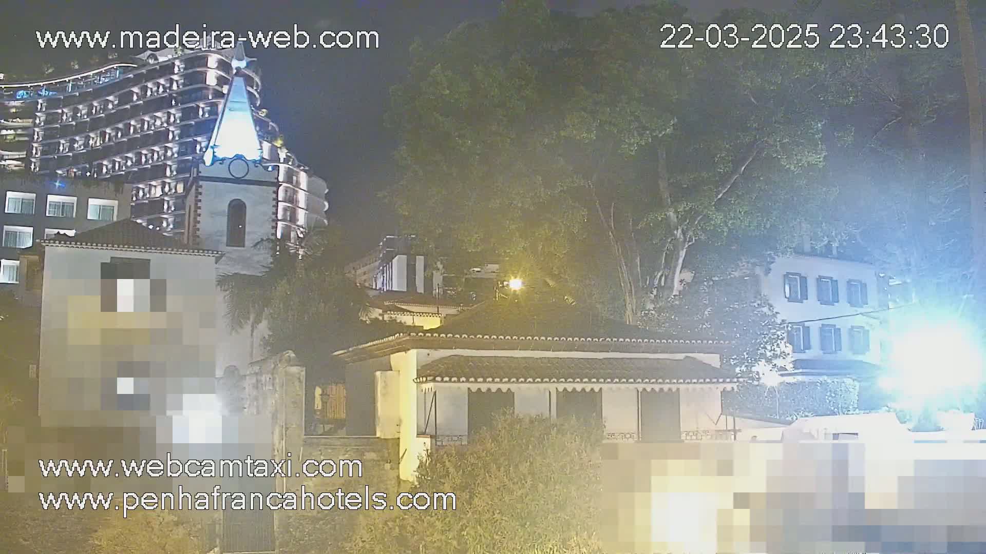 A nighttime view of buildings, including a tall hotel and smaller houses, under a mostly clear sky.