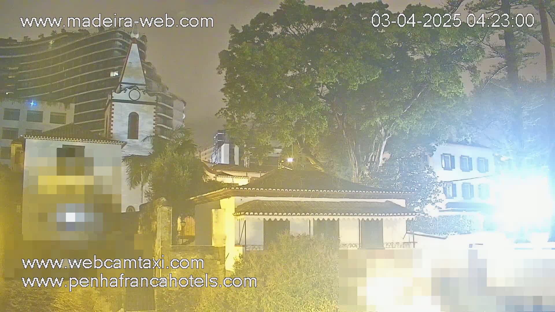 A nighttime view of a town with buildings, trees, and a hazy atmosphere.