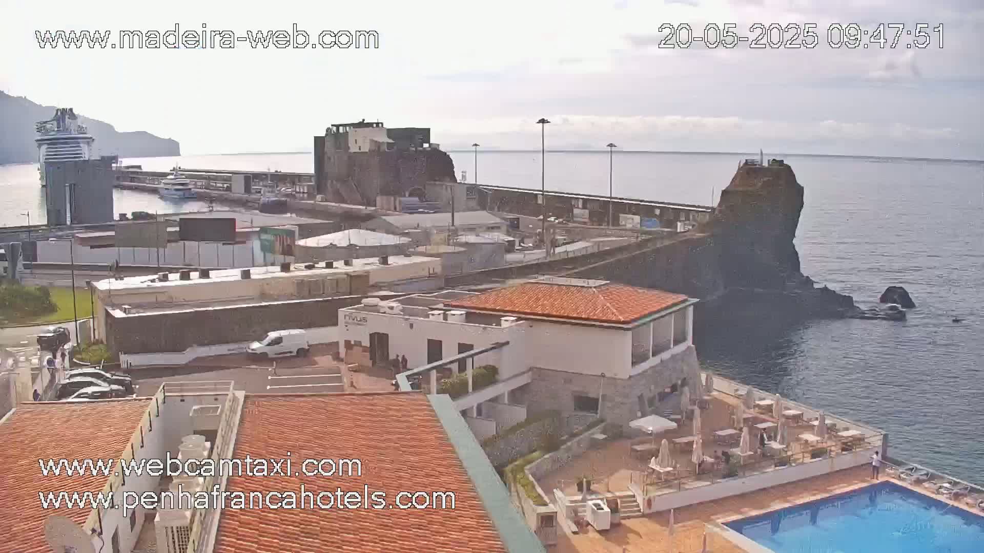 An overcast day reveals a harbor scene with a cruise ship, buildings, and a swimming pool overlooking the ocean.