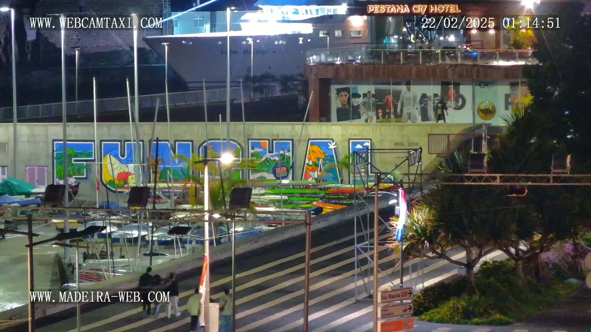 At night, a harbor scene shows a large cruise ship docked next to a building with a mural of the word "Funchal," numerous small boats are moored, and several people are walking near the water.
