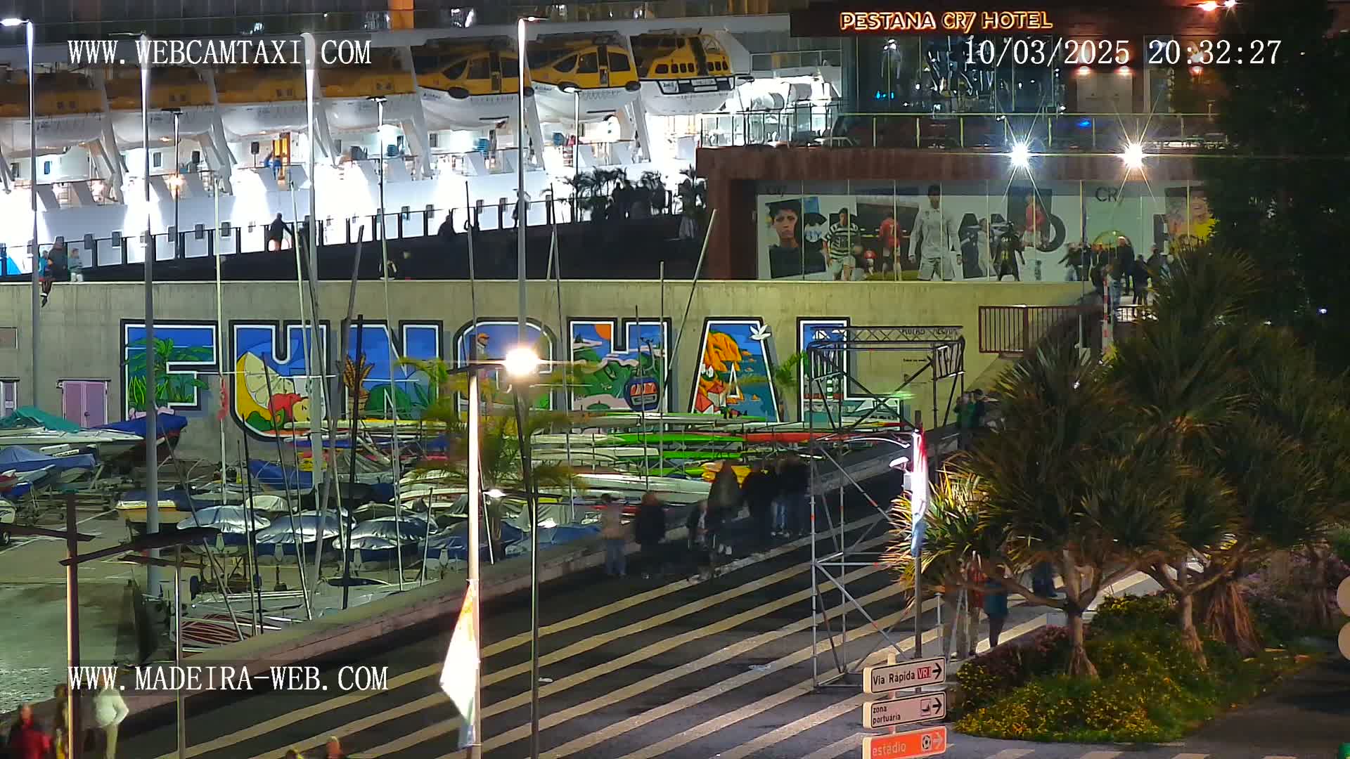 A nighttime harbor scene shows a large mural of "Funchal" on a building, boats docked below, and palm trees and street signs in the foreground.