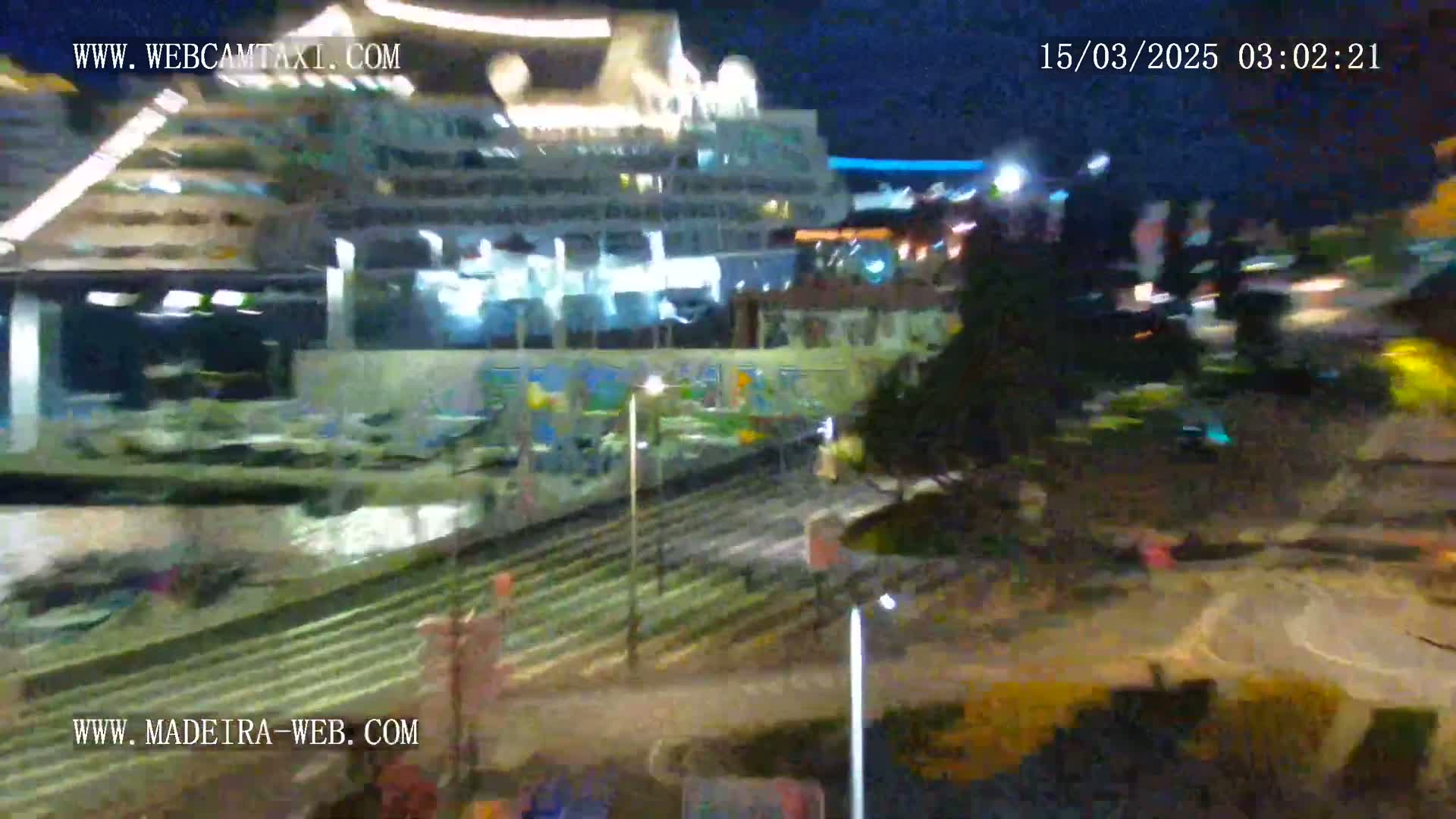 A large cruise ship is docked at night under a dark sky.