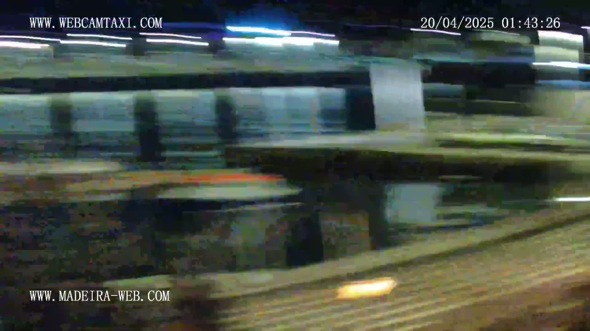 A blurred image at night shows a train moving rapidly past a platform.