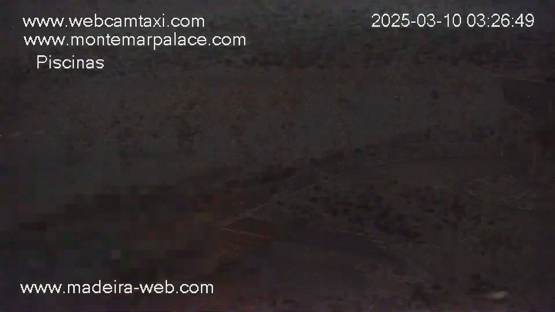 A dark, nighttime image shows an indistinct outdoor scene, possibly a pool area.