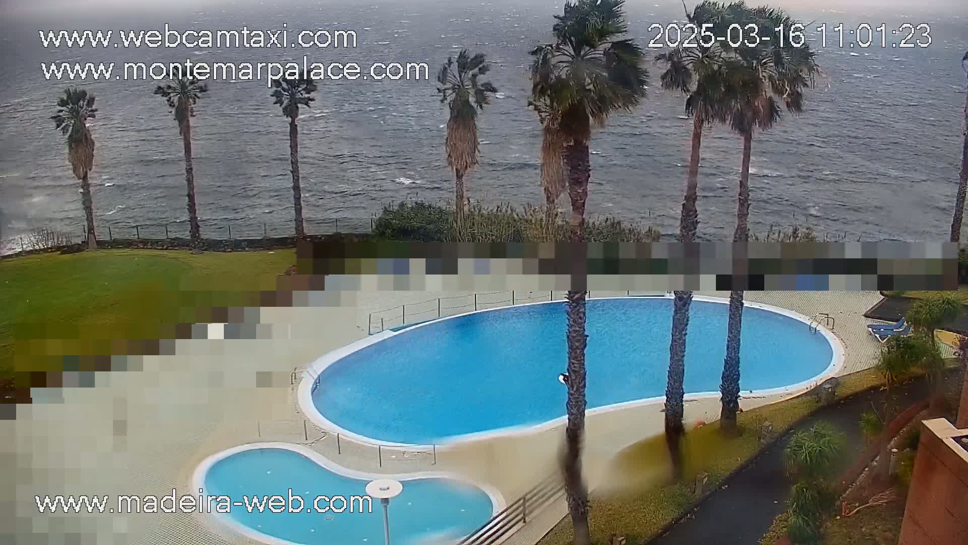 A kidney-shaped swimming pool and a smaller adjacent pool are situated next to a grassy area overlooking a choppy ocean under an overcast sky.