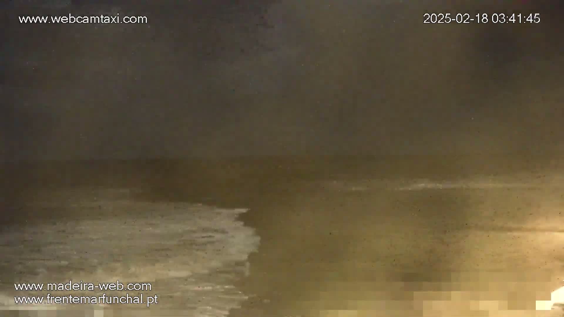 A nighttime, dimly lit ocean scene shows waves crashing on a shore under a dark, overcast sky.