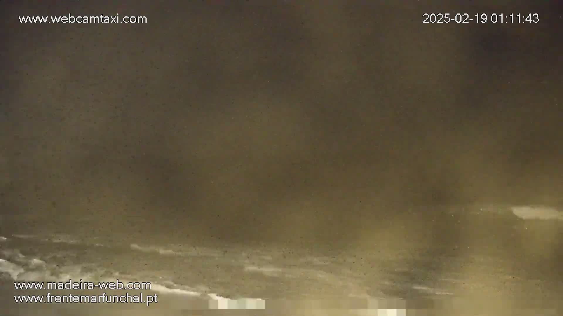 A dark, hazy scene shows a body of water with small waves under a night sky.