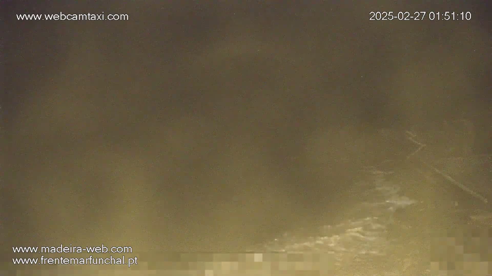 A nighttime, hazy, blurry view shows dark water with some lighter areas suggesting waves or movement.