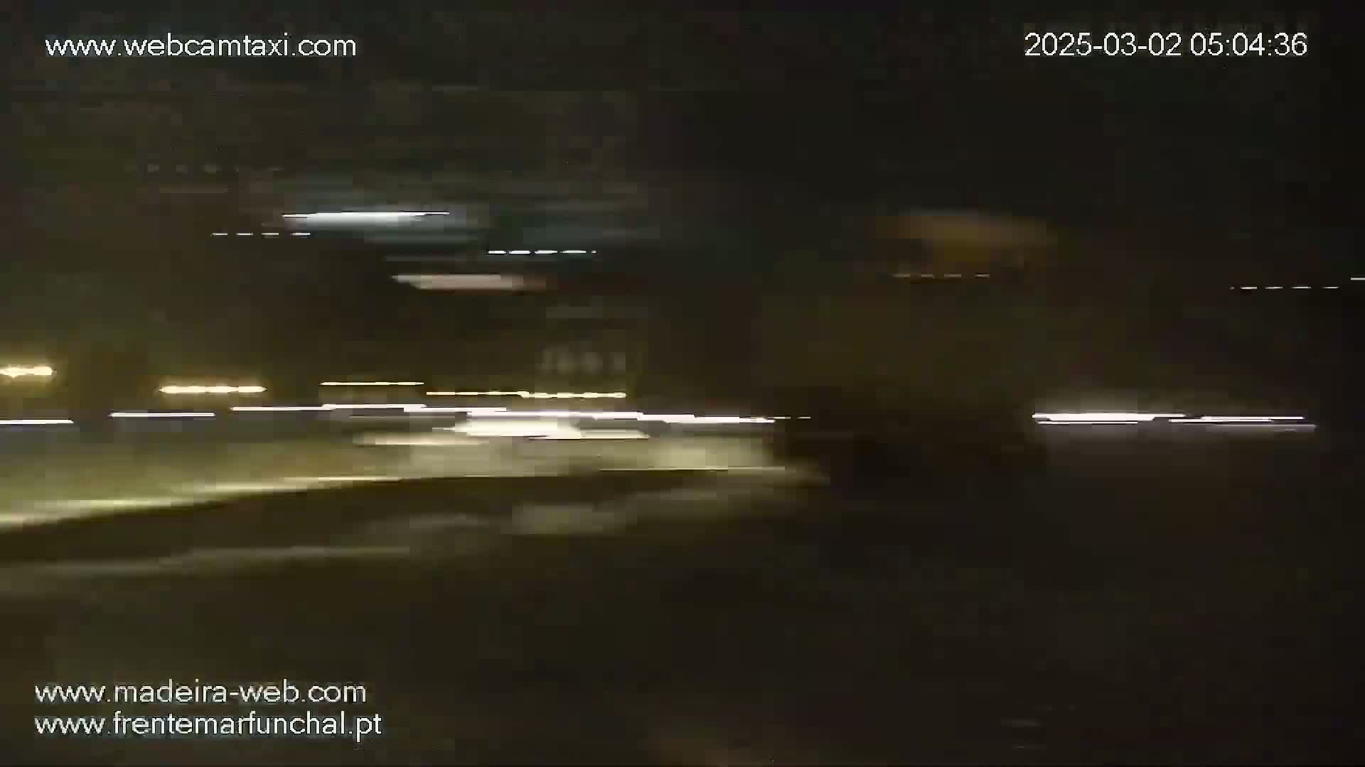 A nighttime view from a vehicle shows blurred lights of other vehicles on a road.