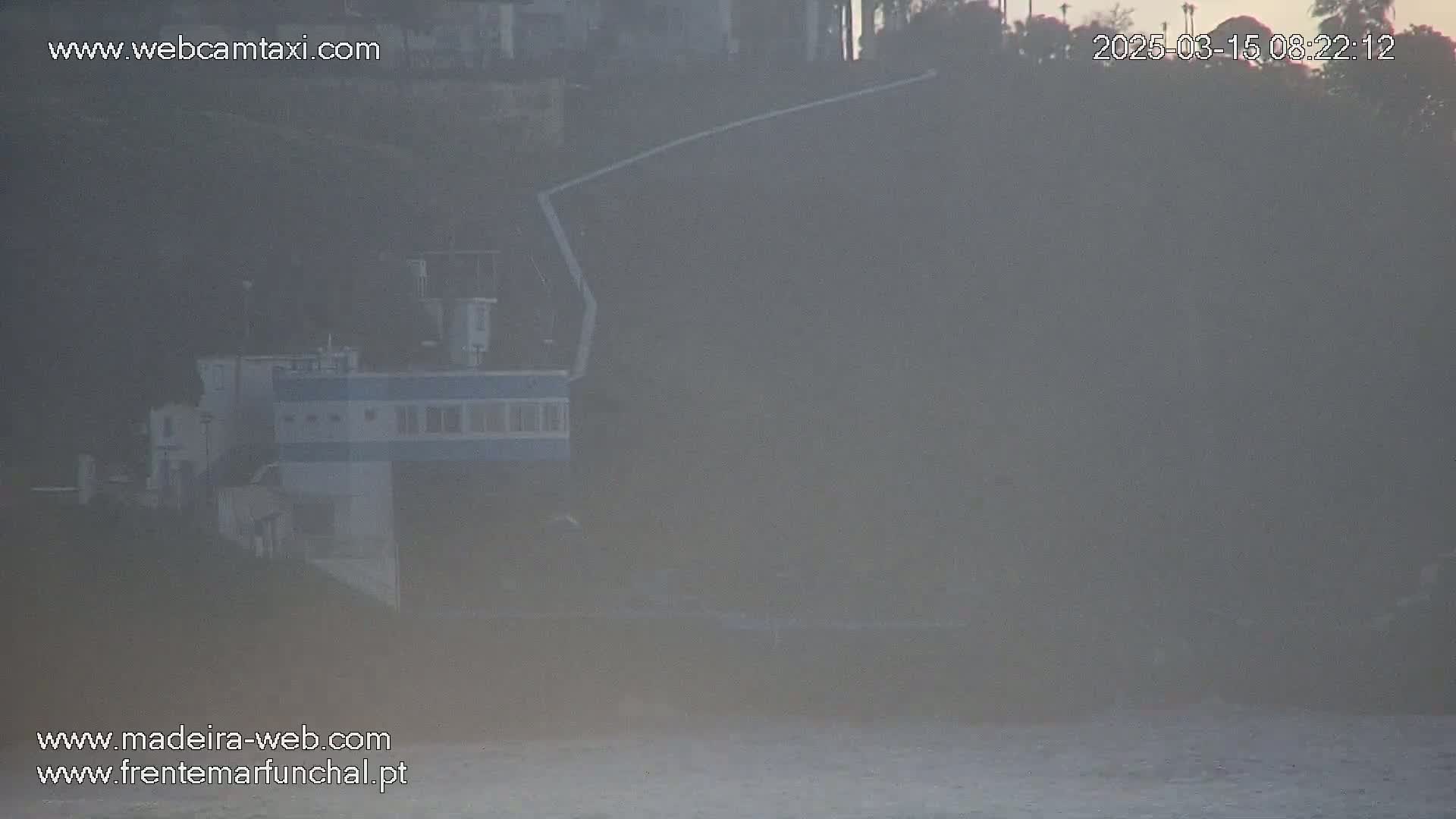A hazy, foggy view shows a building near the water, partially obscured by mist.