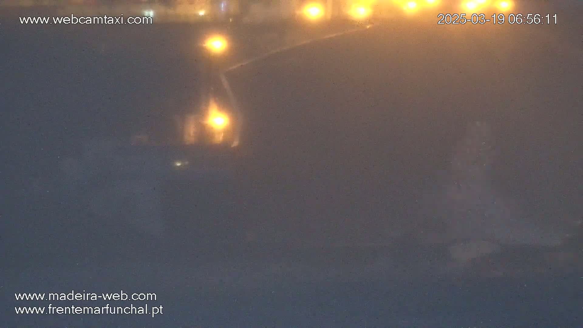 A blurry, foggy nighttime image shows indistinct shapes and faint lights.