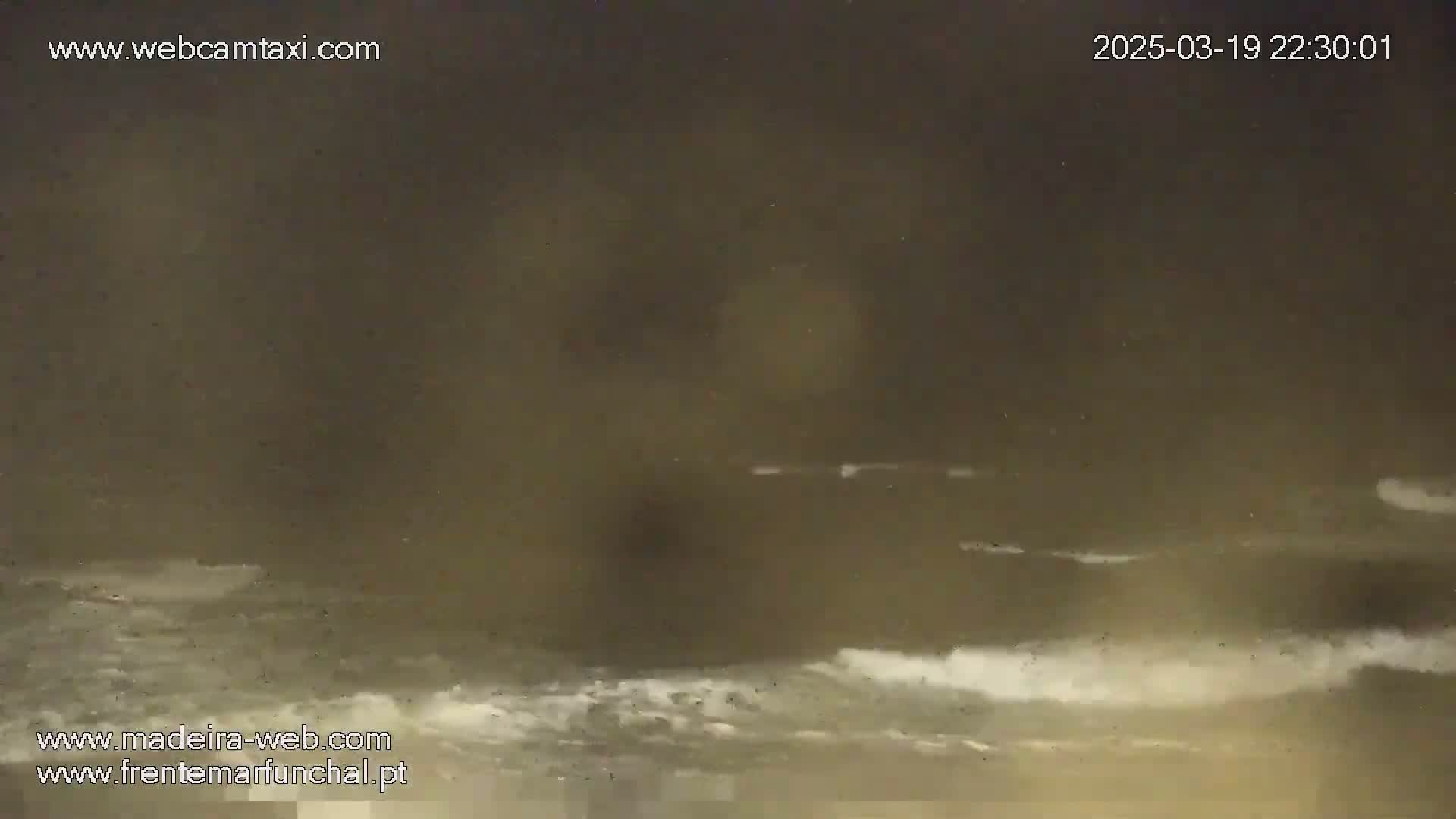 A nighttime view of dark, choppy ocean waves under a hazy, dark sky.