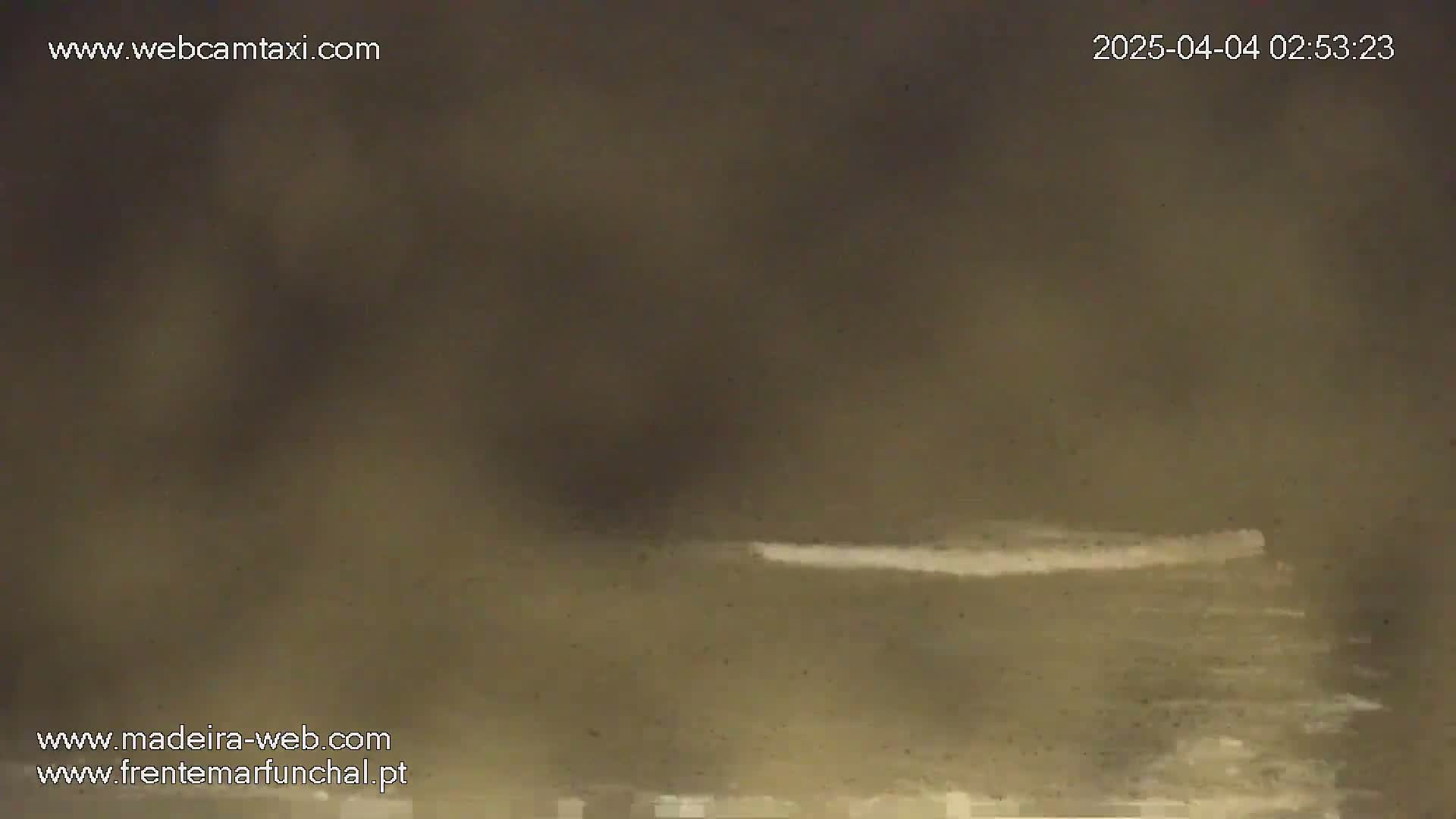 A hazy, dark-brown body of water shows a thin white line of waves or foam near the horizon.