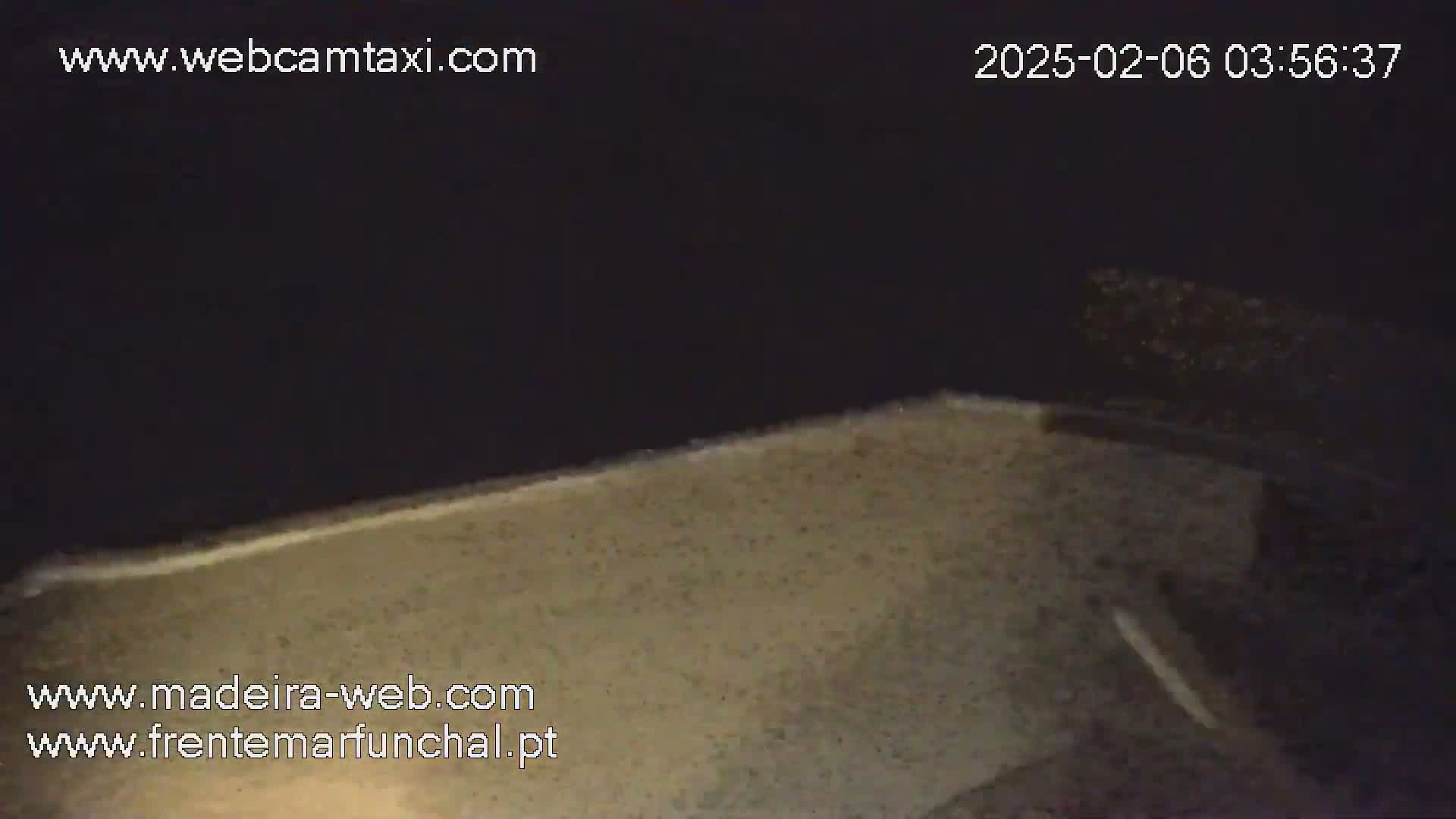 A nighttime, low-angle view shows a sandy beach under a dark sky.