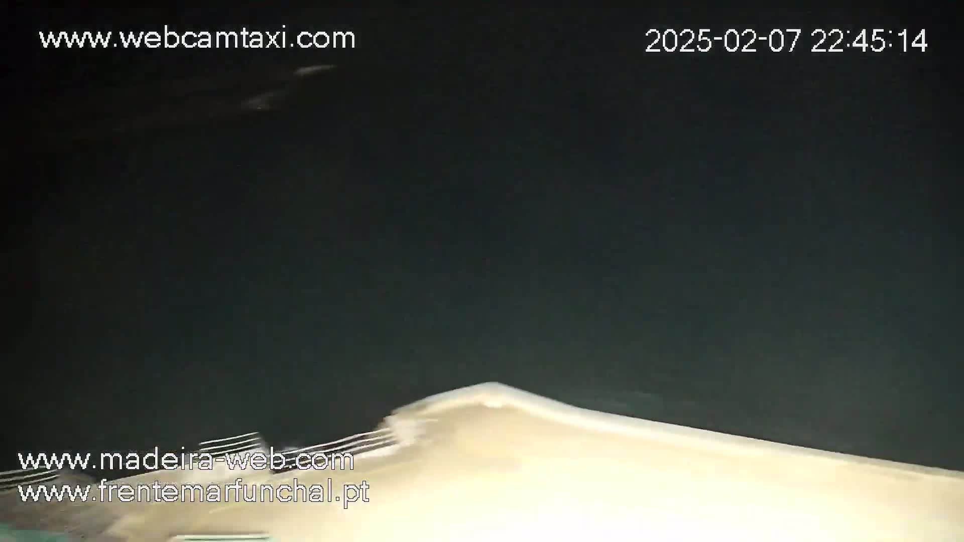 A nighttime, low-angle view shows a dark body of water with a light-colored surface appearing at the bottom of the frame.