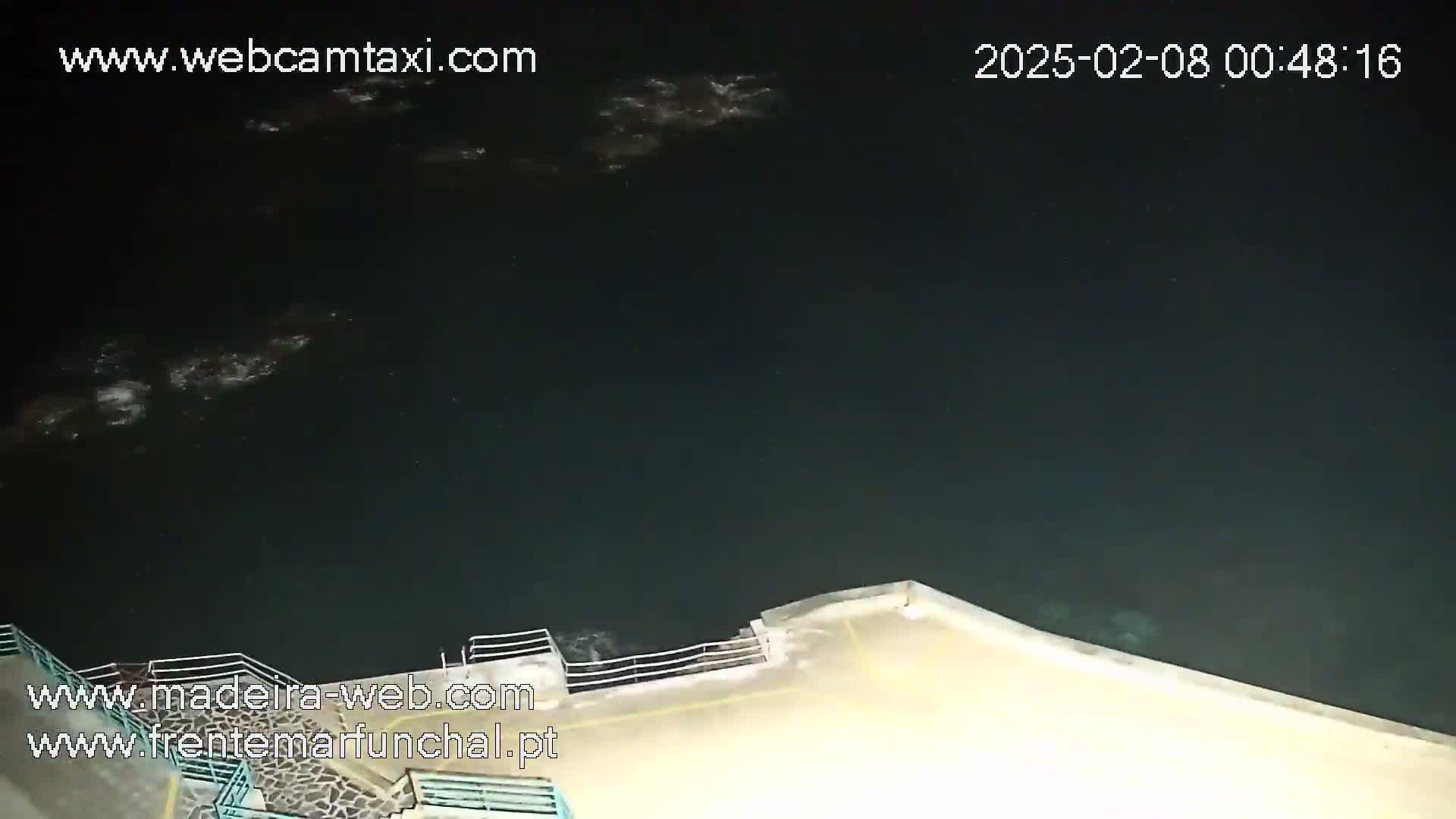 A nighttime, high-angle view shows dark water lapping against a concrete embankment.