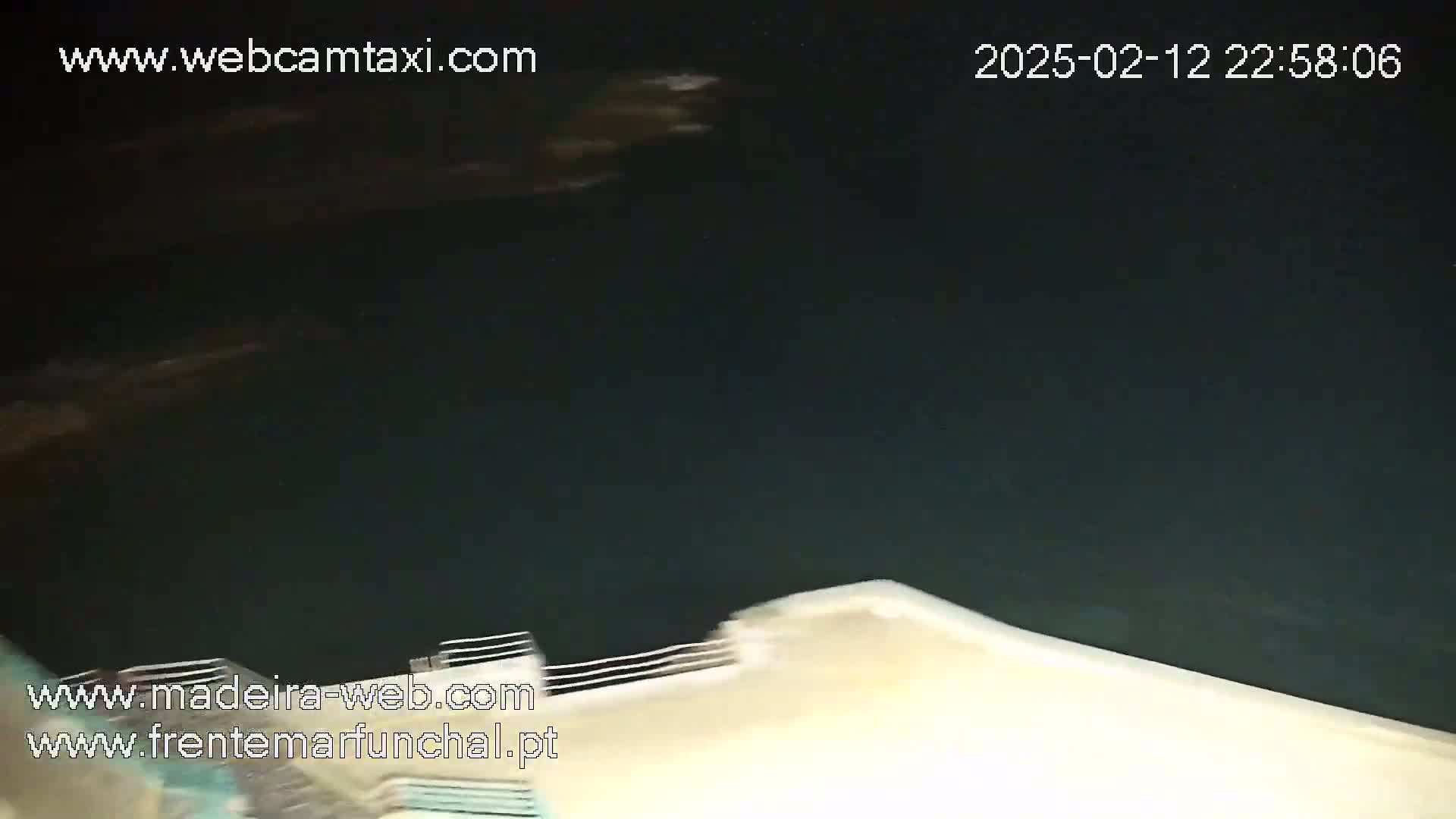 A nighttime view of dark water next to a light-colored surface, possibly a dock or wall.
