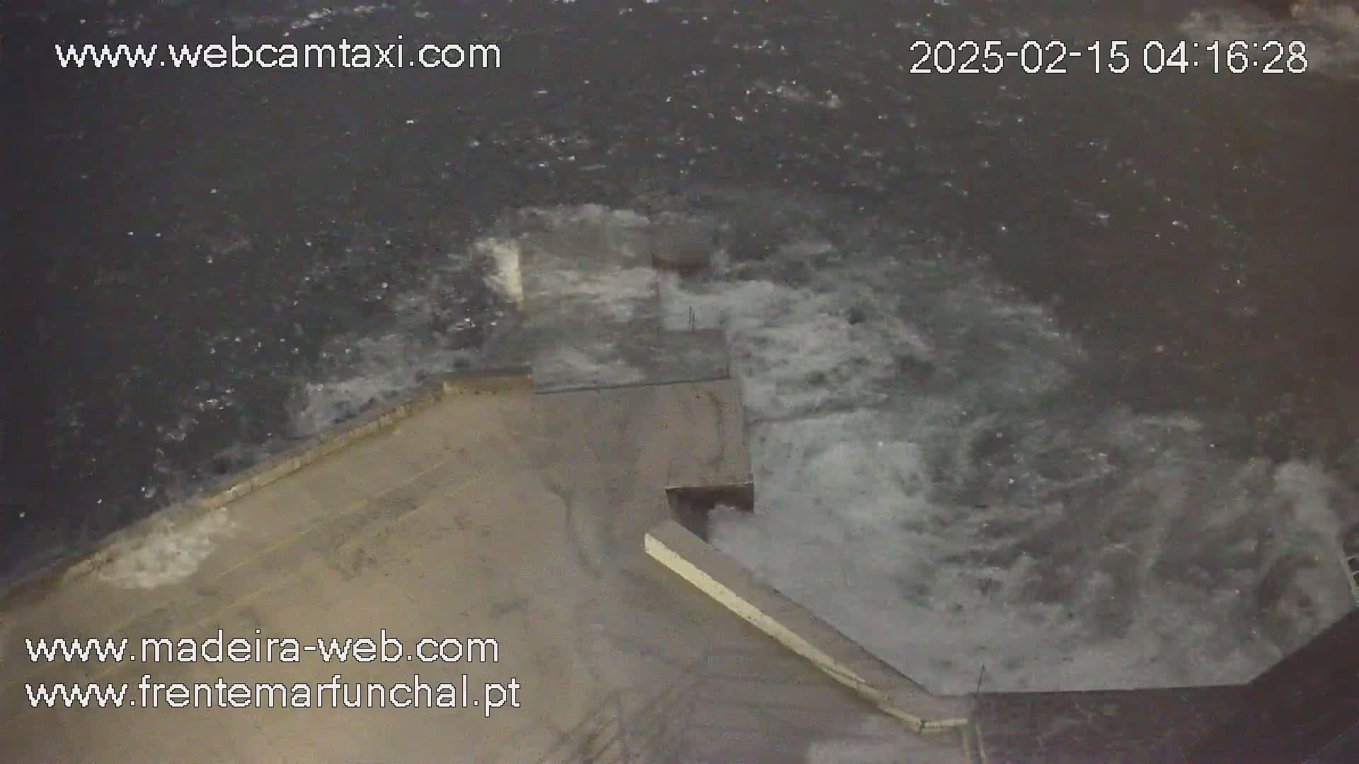 Rough, dark water crashes against a concrete structure during a stormy night.