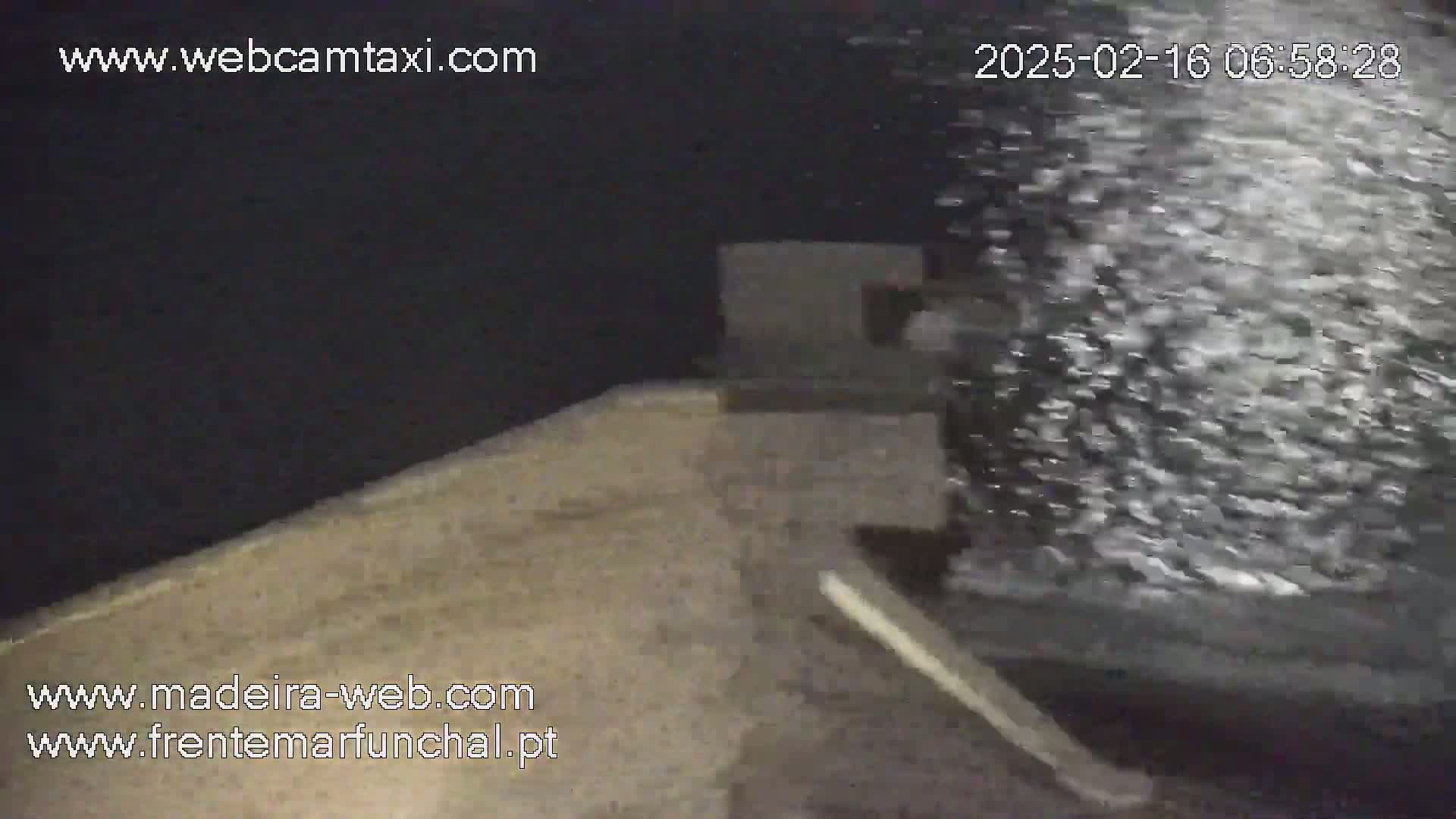 A dark gray structure is partially visible in a nighttime scene with heavy splashing water in the foreground.