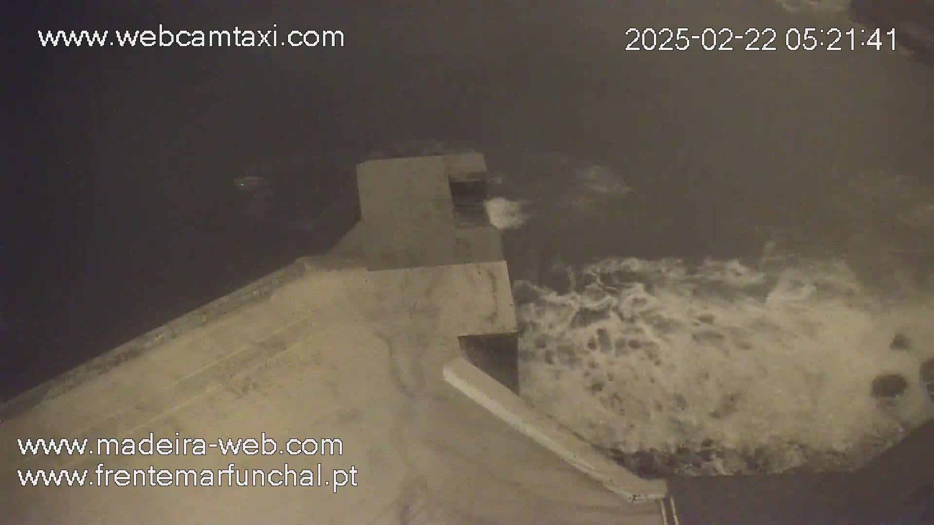A high-angle, nighttime view shows churning water flowing from a concrete structure into a dark body of water.