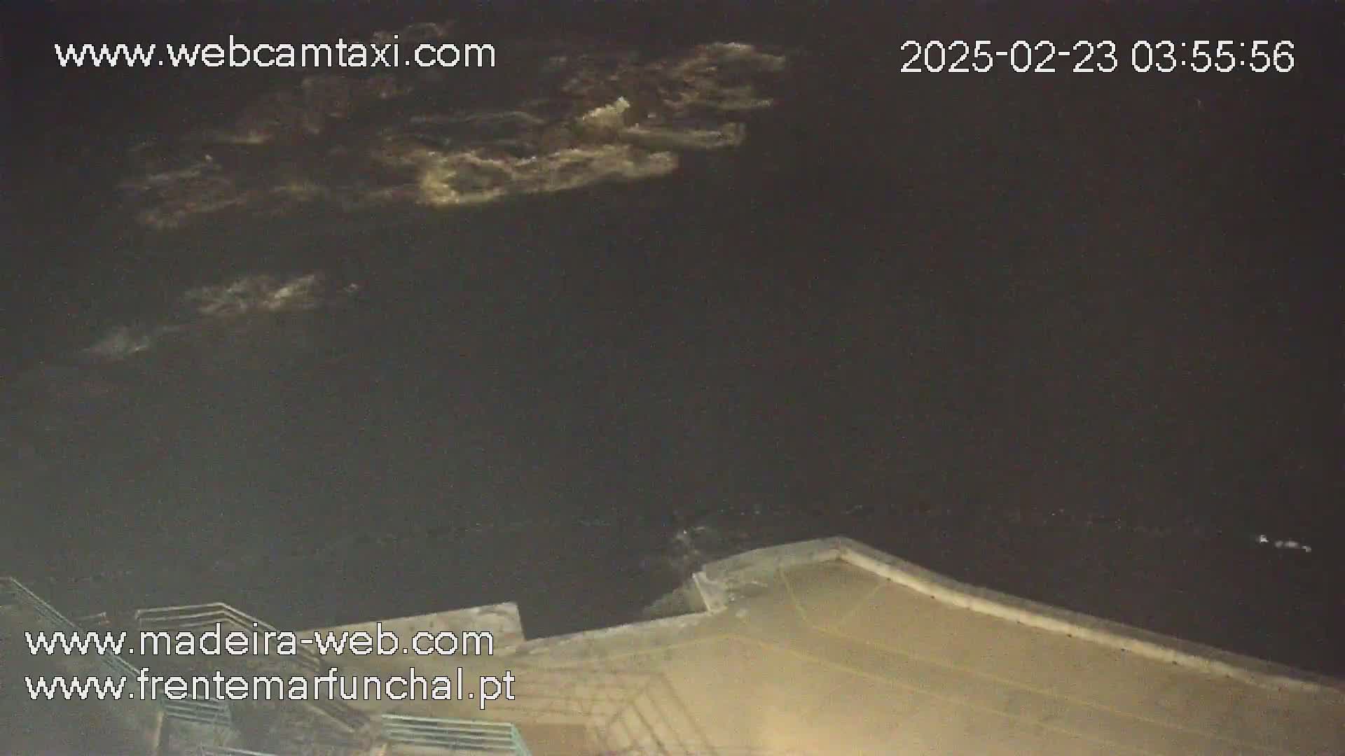 A nighttime, cloudy view of a body of water from an elevated position overlooking a concrete structure.