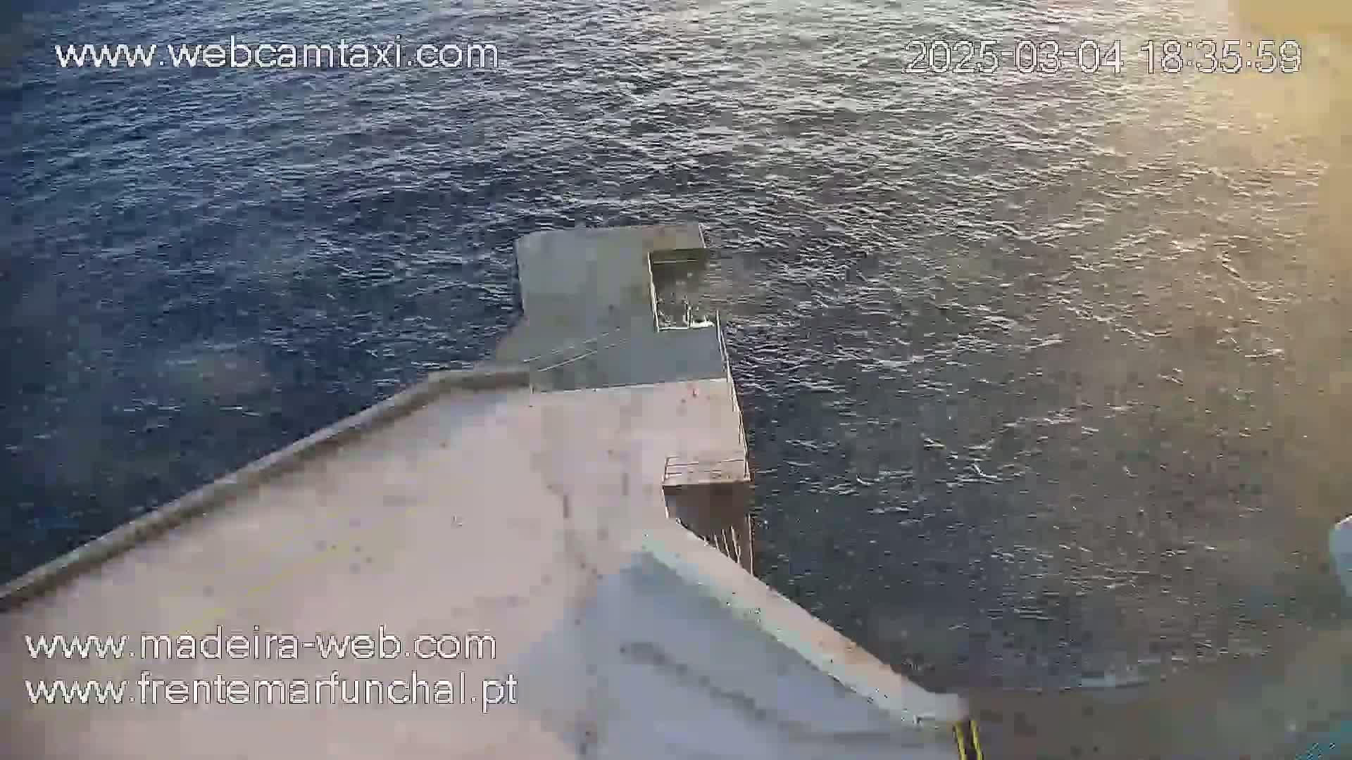 A concrete structure extends over dark, choppy water.