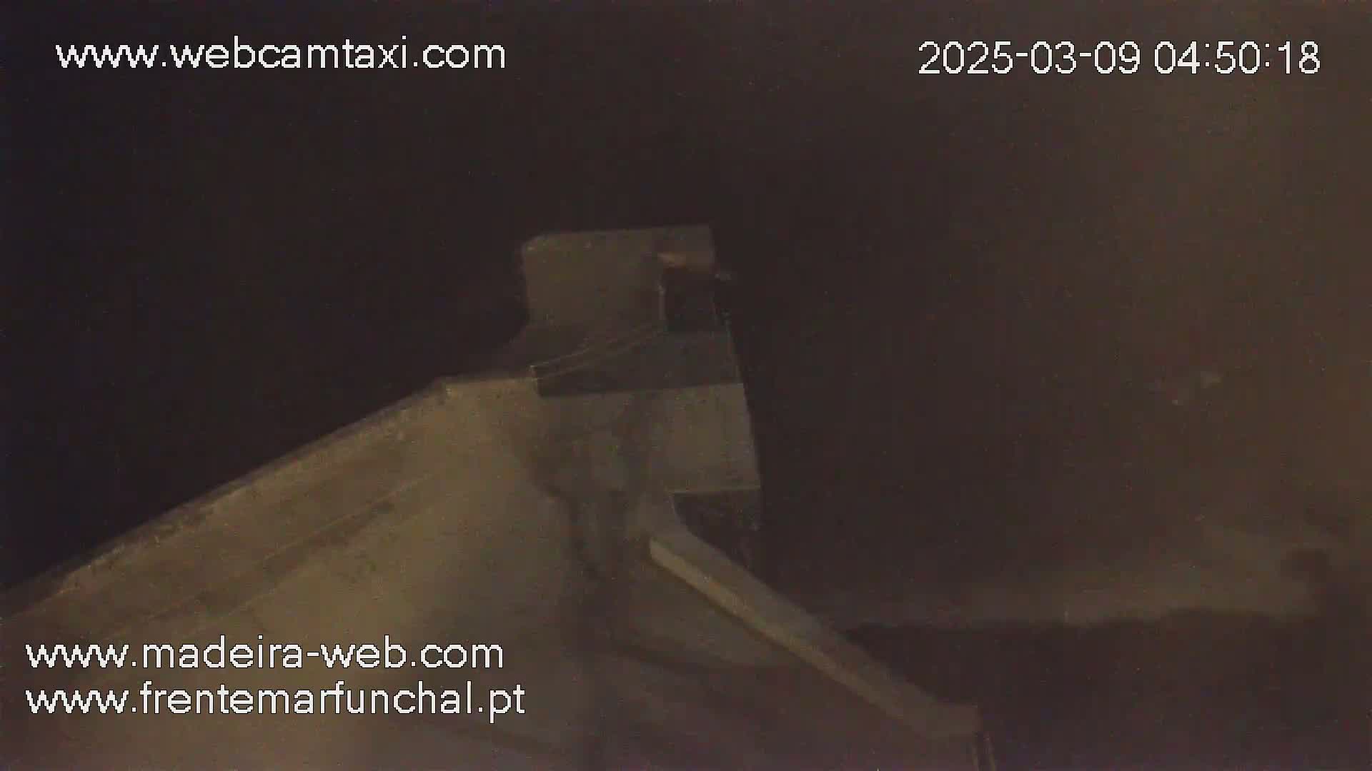A nighttime, low-light view of a concrete structure, possibly a wall or part of a building.