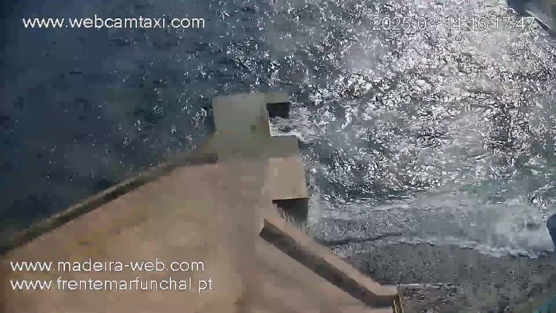 A high-angle view shows choppy water crashing against a concrete structure.