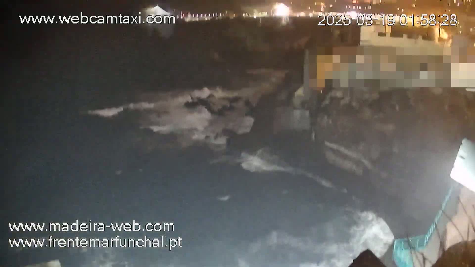 A nighttime coastal scene shows dark, rough water with whitecaps crashing against a rocky shore under a dark sky.