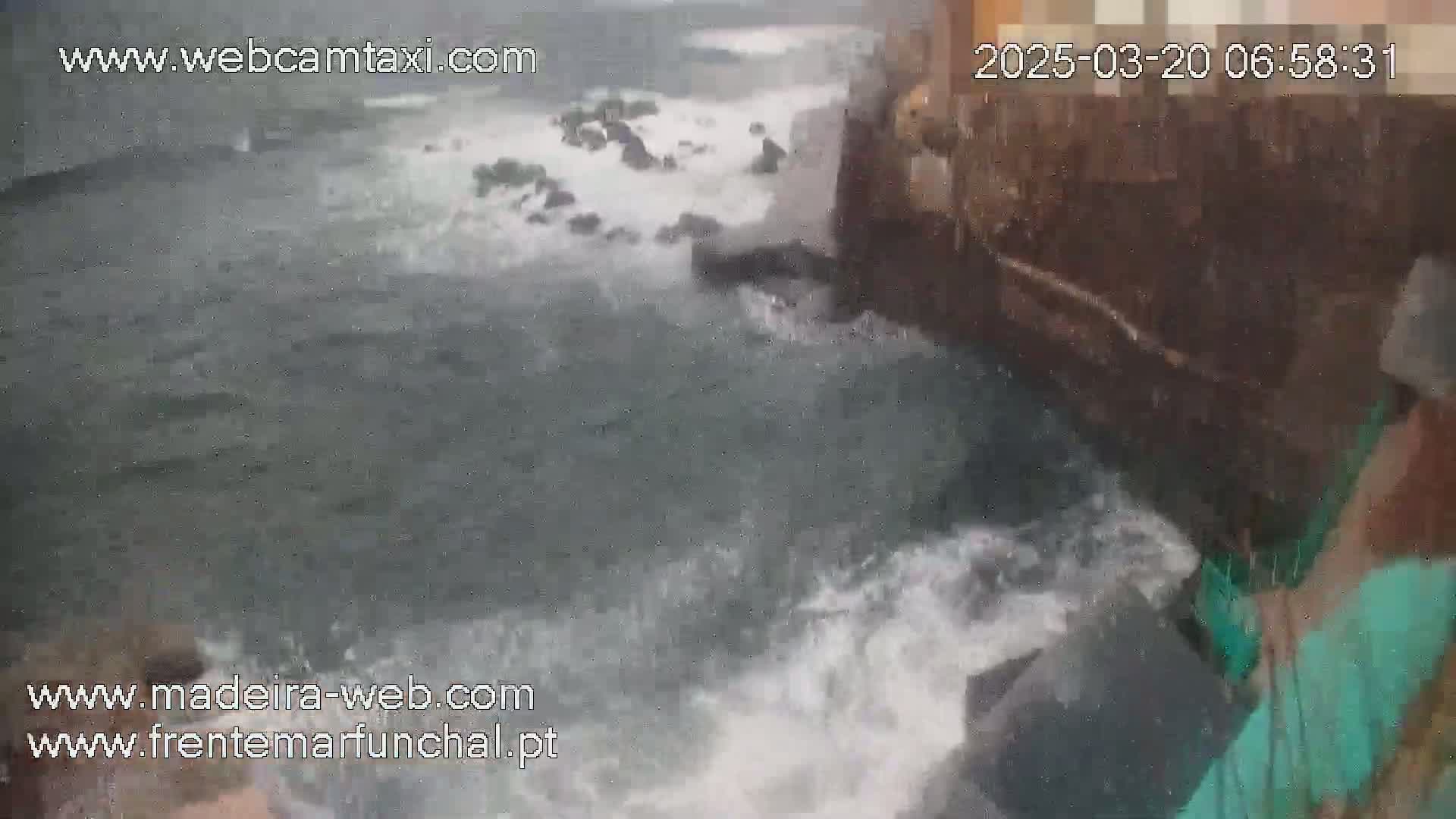 Rough ocean waves crash against a rocky structure during stormy weather.