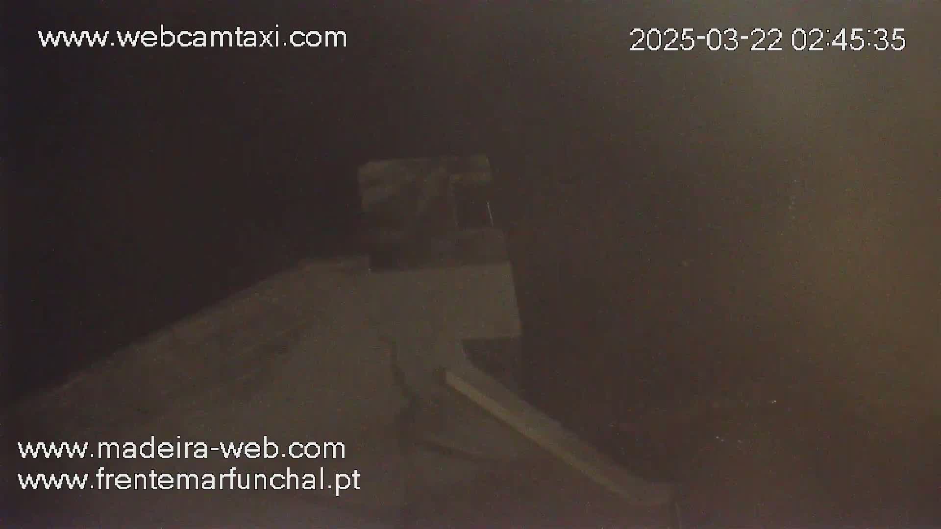 A low-light, nighttime image shows a portion of a building's exterior with a ramp or incline.