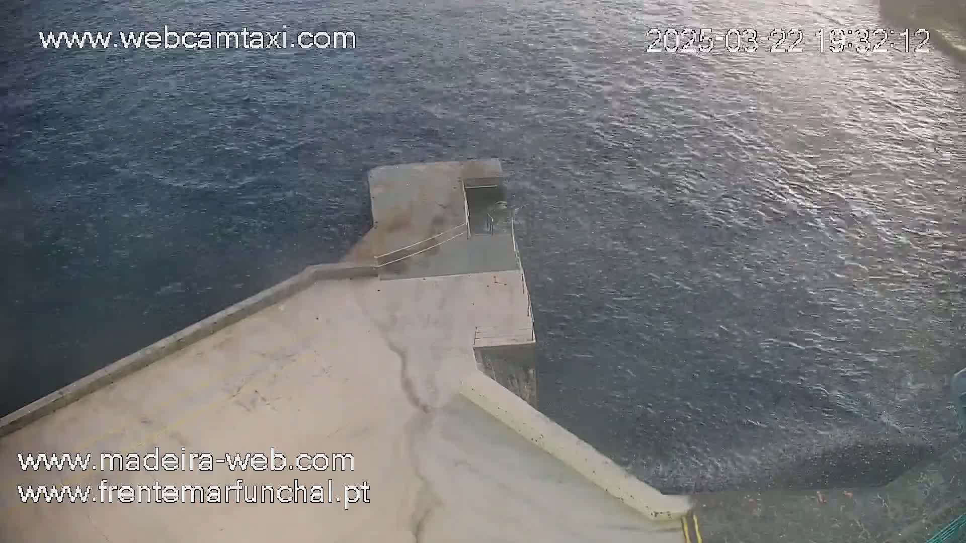 A concrete platform extends into a dark, choppy body of water.