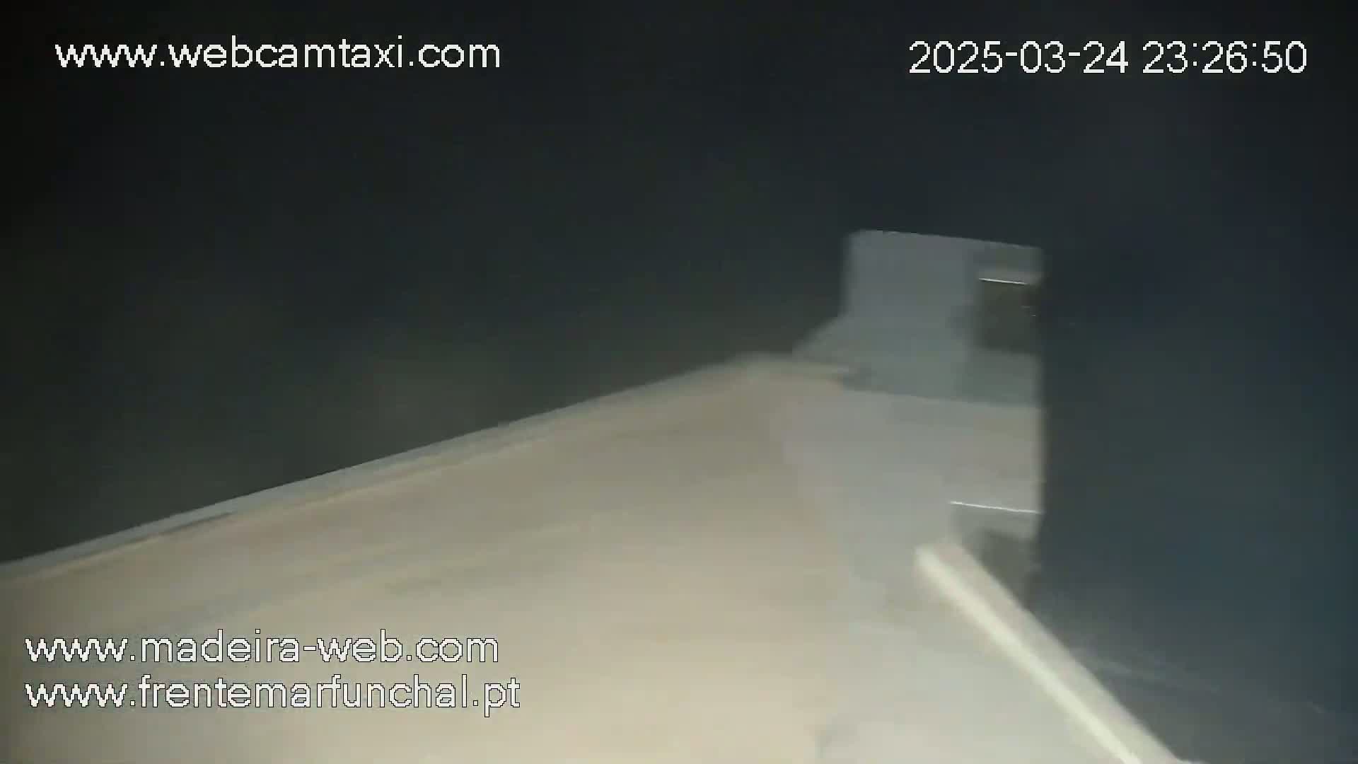 A blurry image shows a light-colored, possibly tiled, floor and a dark wall, possibly indoors.