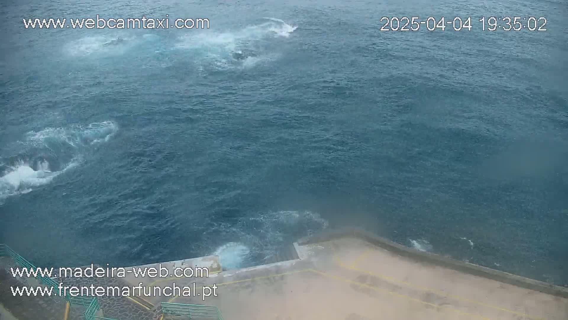 A high-angle view shows choppy ocean water splashing against a dock.