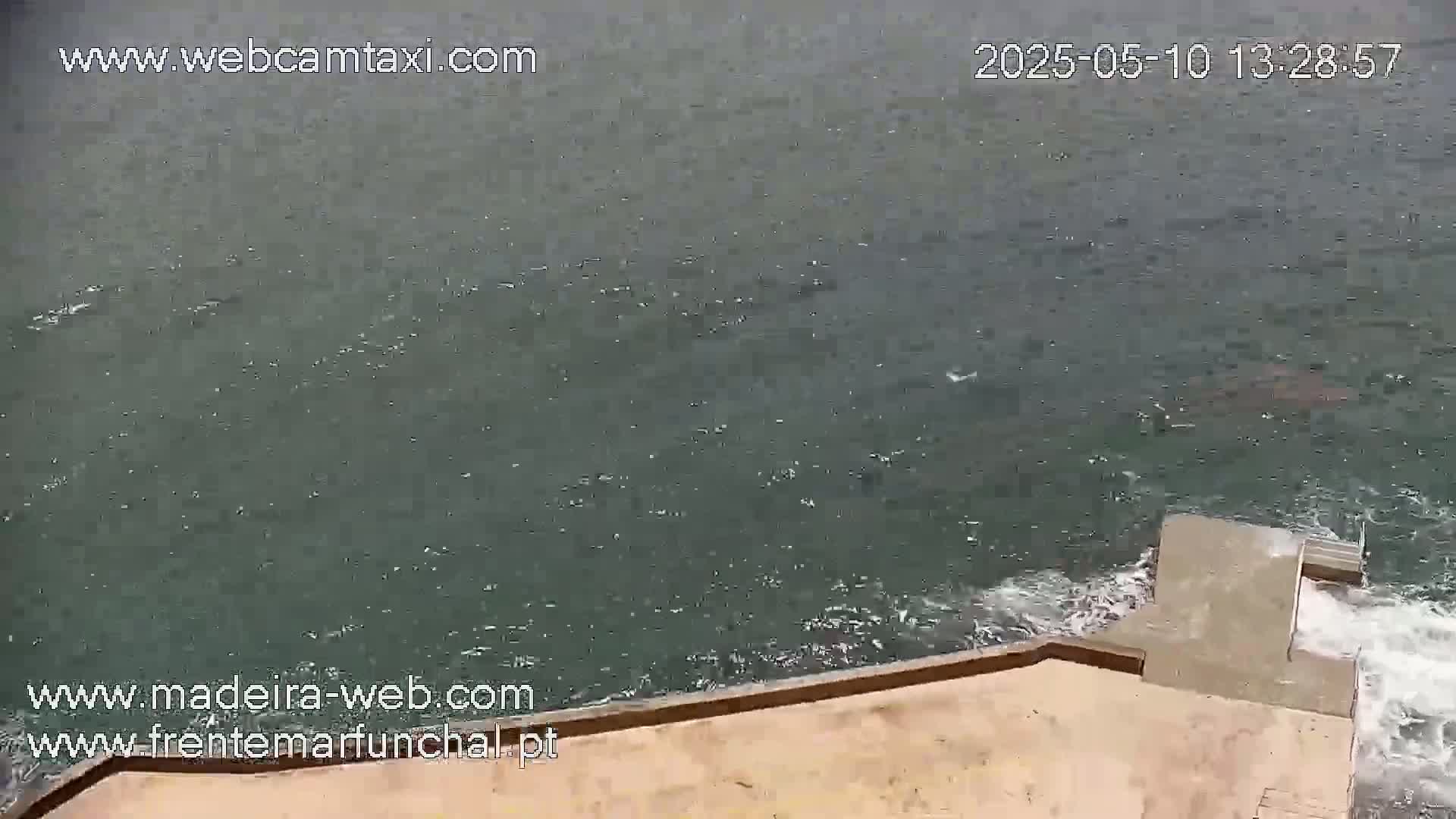 A high-angle view shows a choppy body of water lapping against a concrete structure with steps leading down into the water.