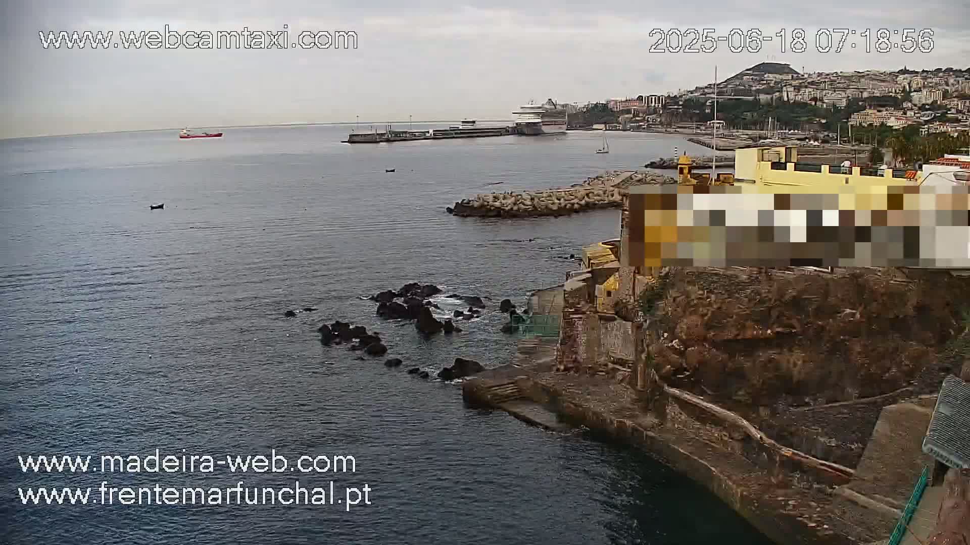 A cruise ship is docked in a harbor next to a rocky coastline under an overcast sky.