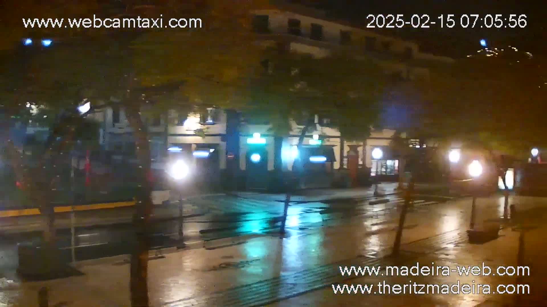 A rain-slicked street at night, reflecting the lights of buildings and street lamps.