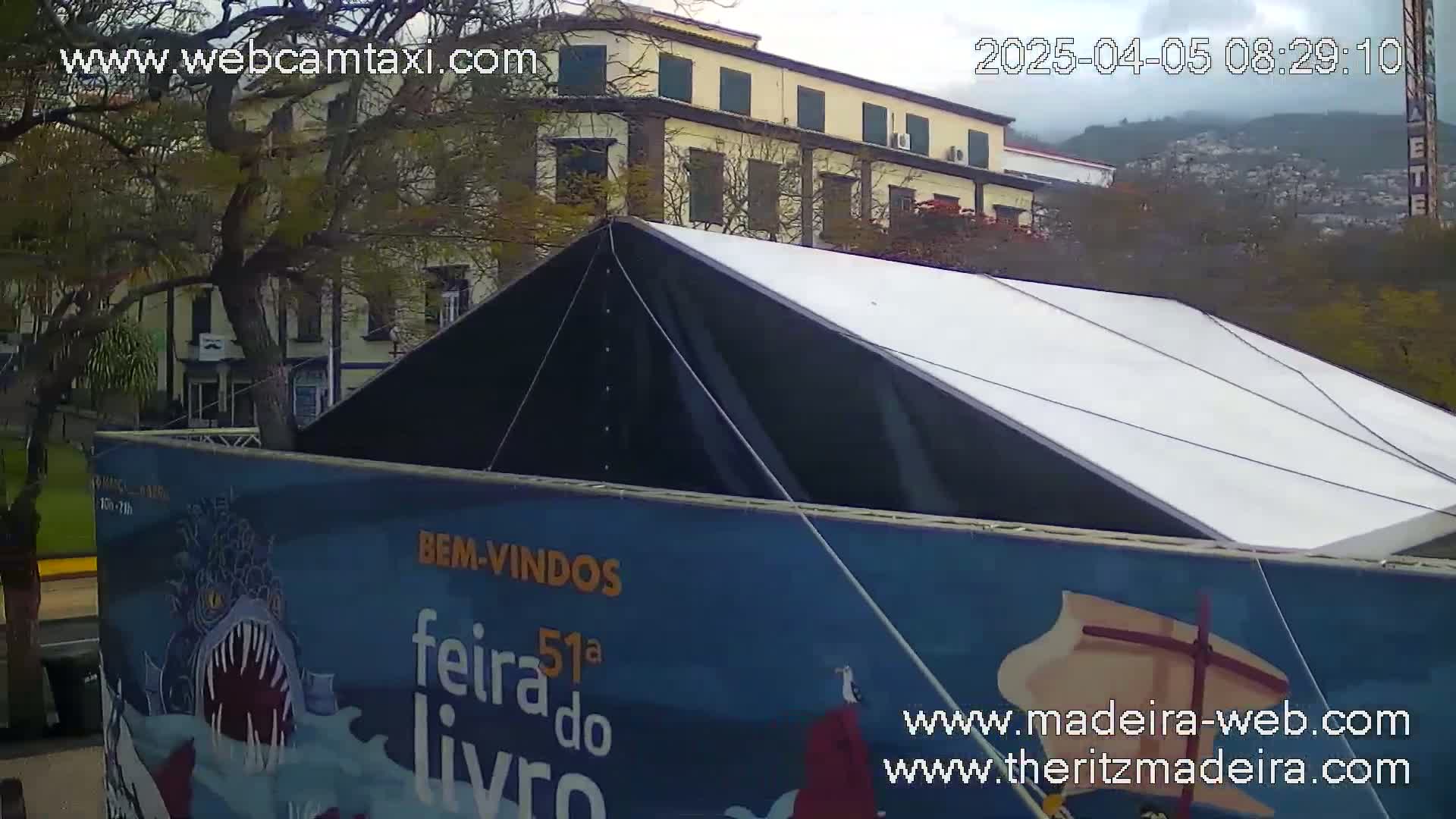 A large black and white tent sits in front of a multi-story building under a cloudy sky.