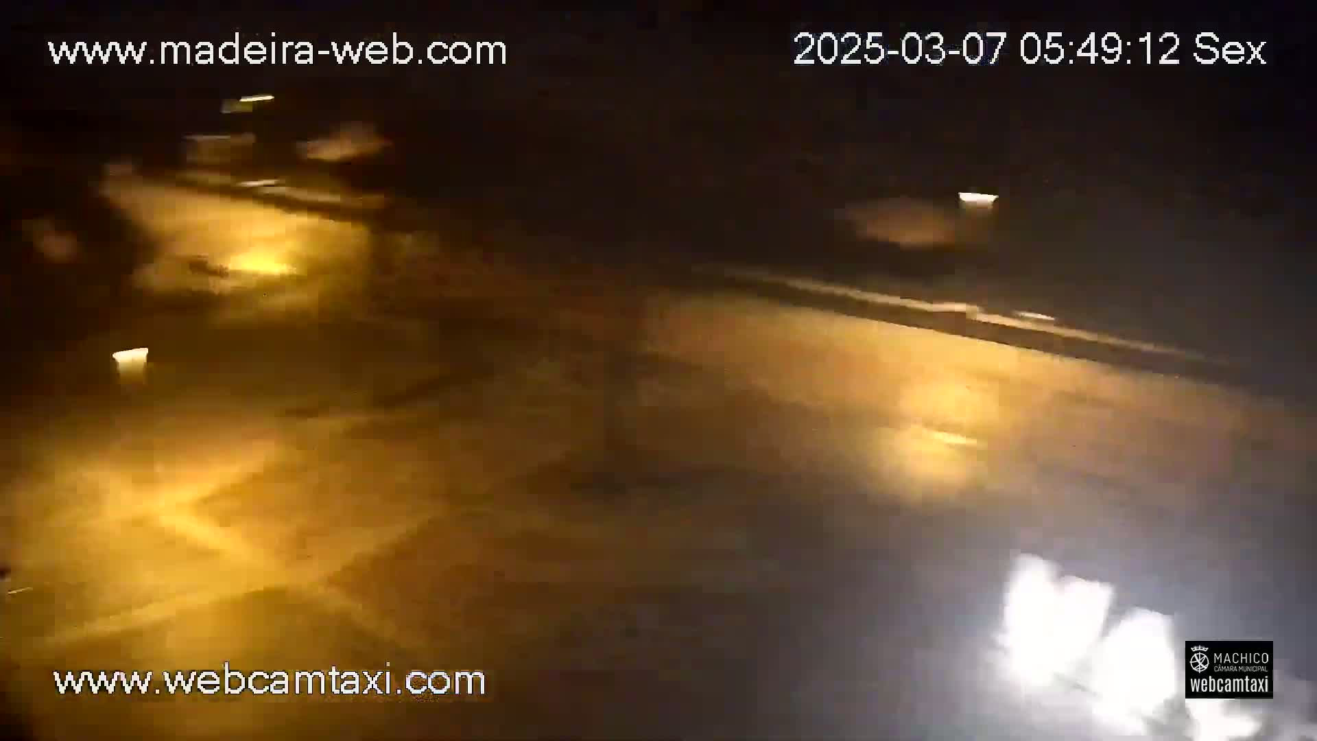 A nighttime, blurry view of a road with some vehicle headlights visible.