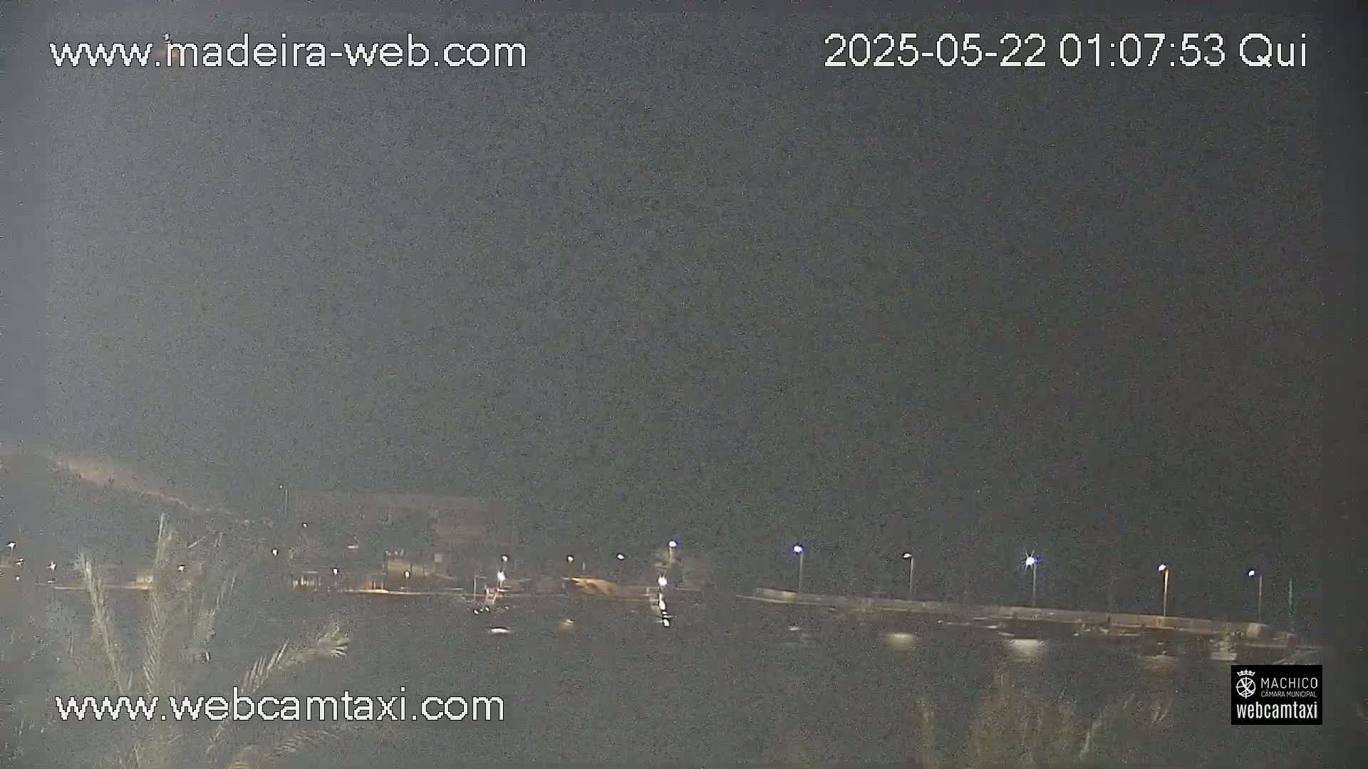 A nighttime, low-light view of a dimly lit roadway and waterfront area.