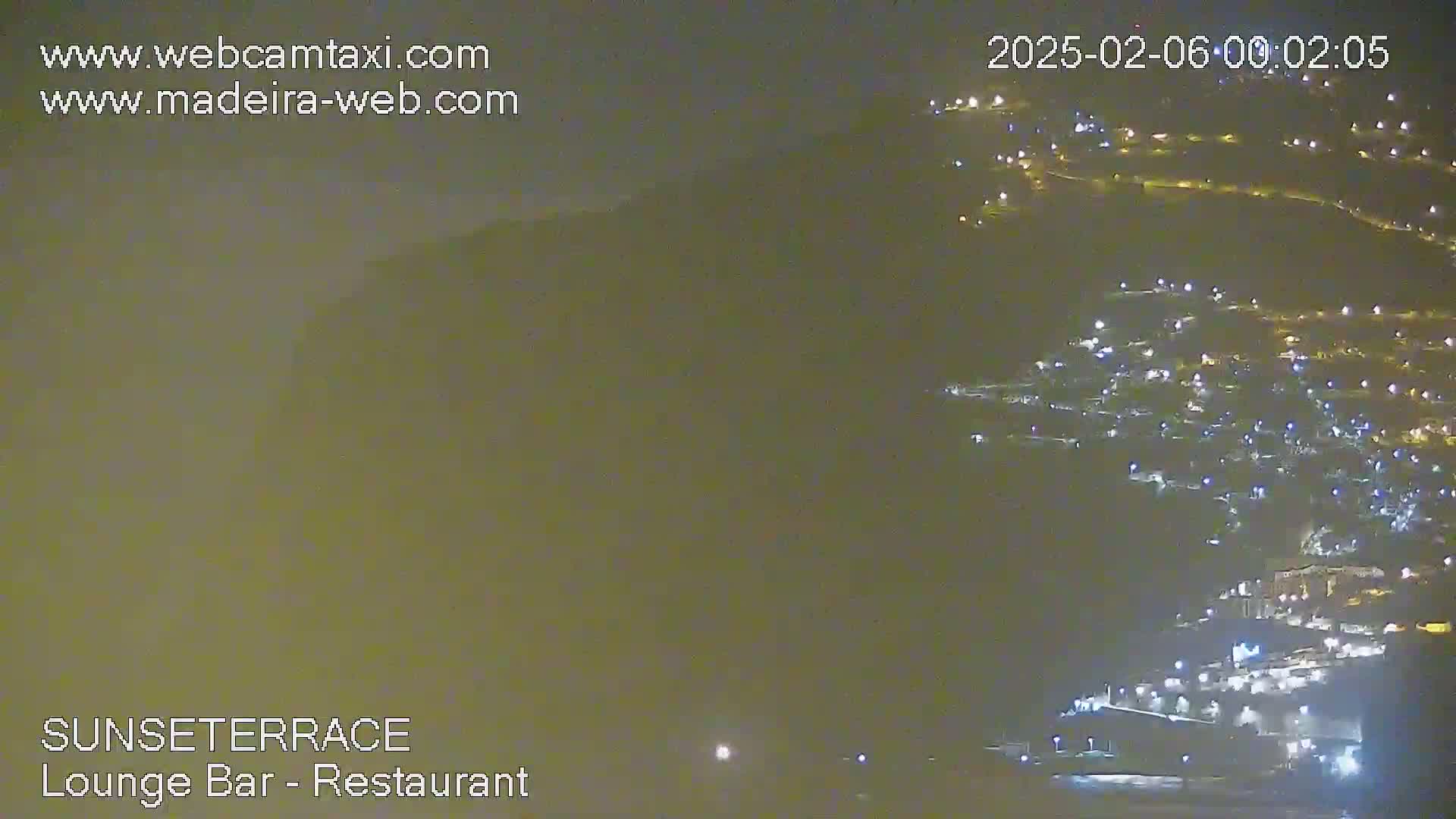 A hazy night view shows numerous lights scattered across a hillside.