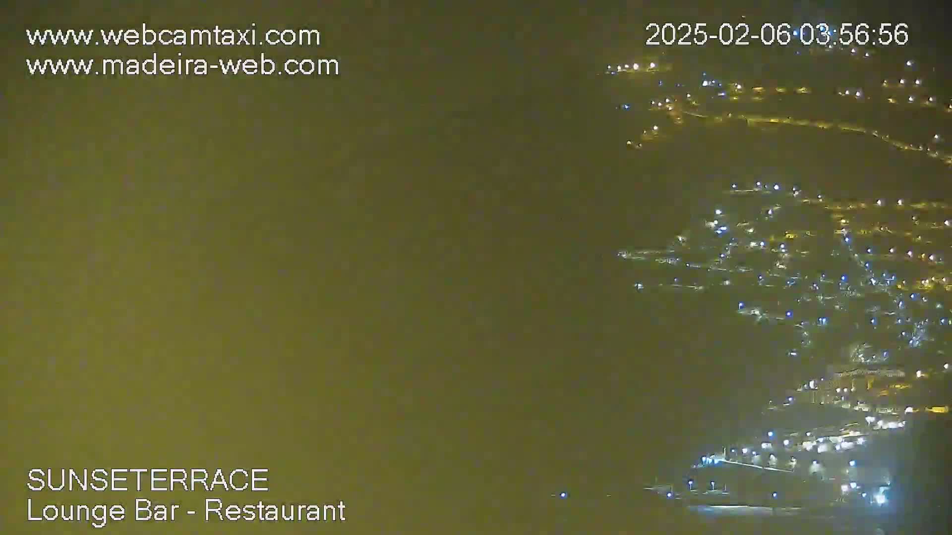 A hazy, nighttime view shows numerous lights scattered across a hillside.