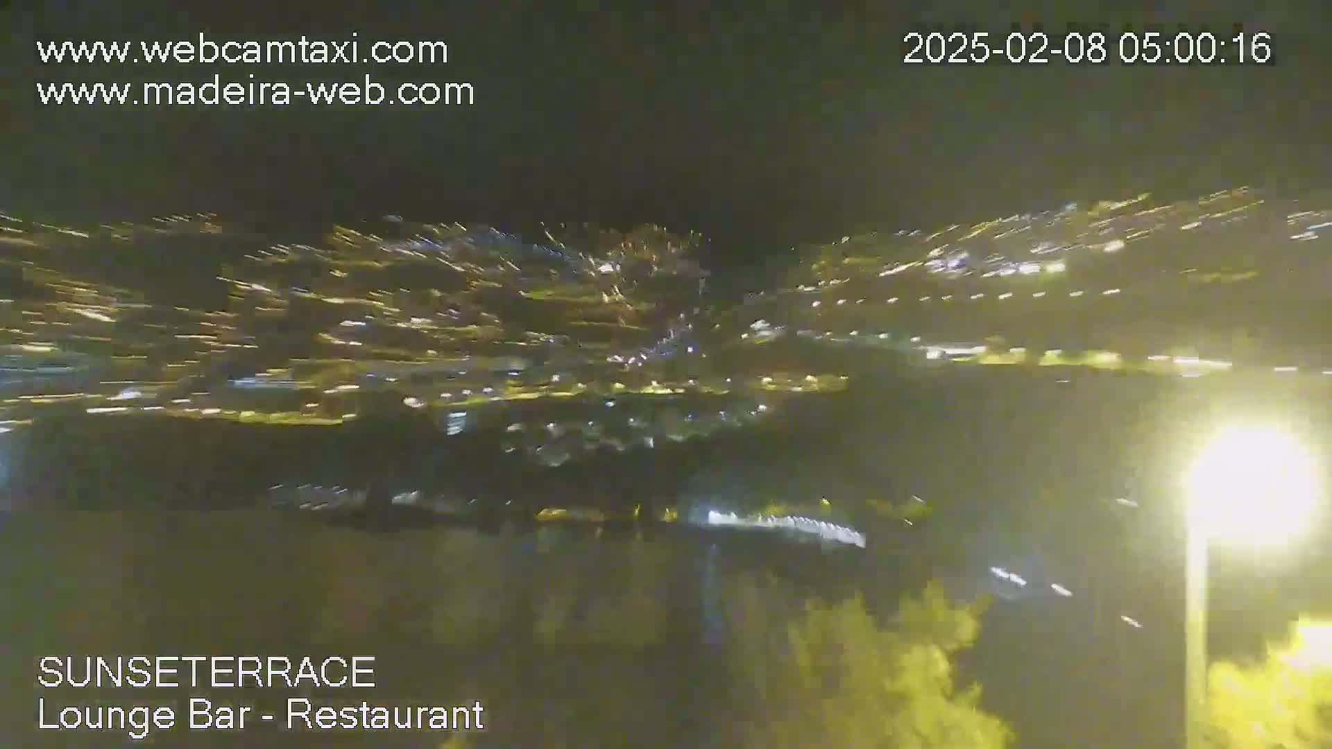 A nighttime, high-angle view shows blurred streaks of light suggesting motion, likely from vehicles, along a road or highway.