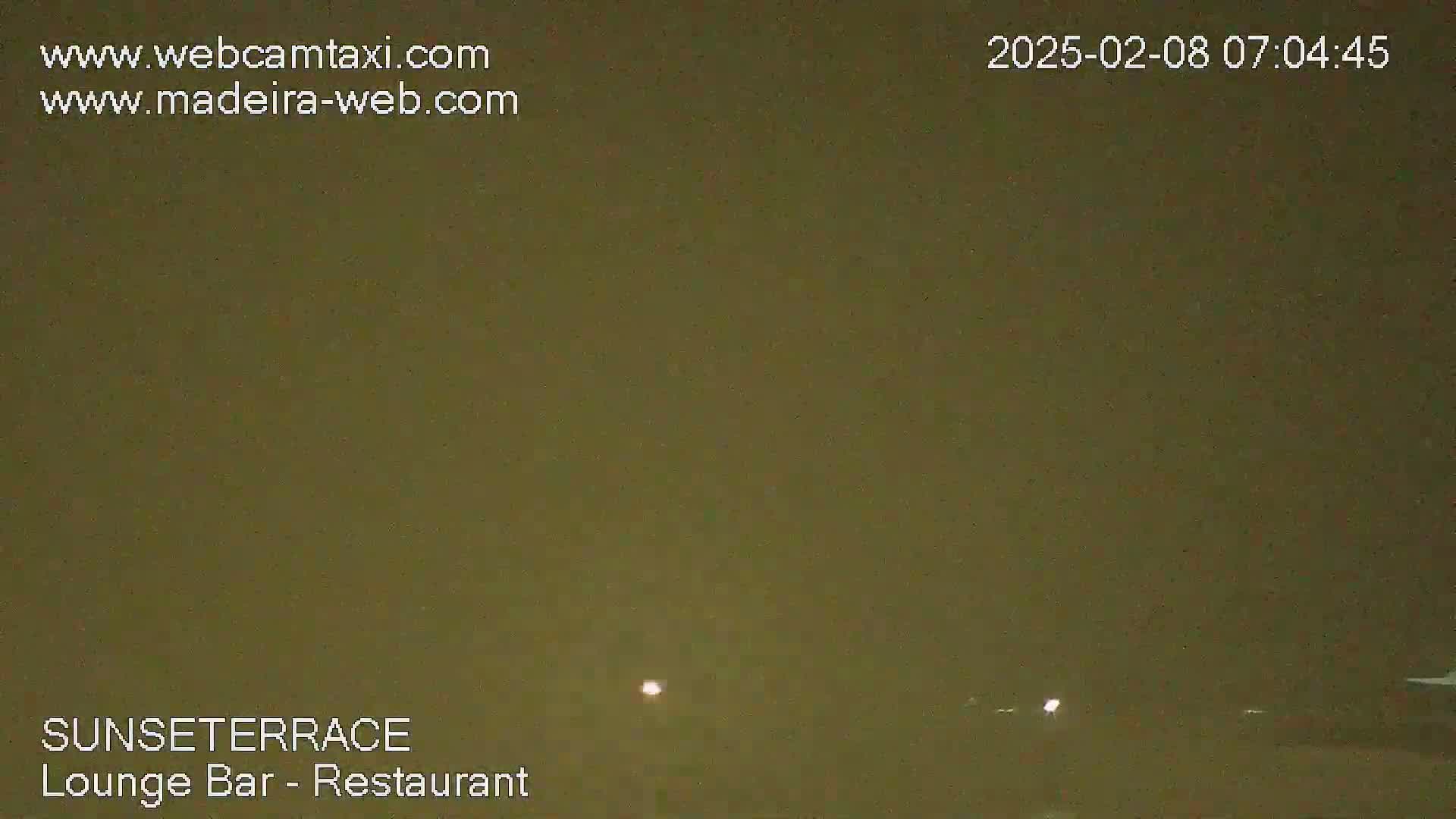 A dark, muted-green night scene shows two faint lights in the distance.