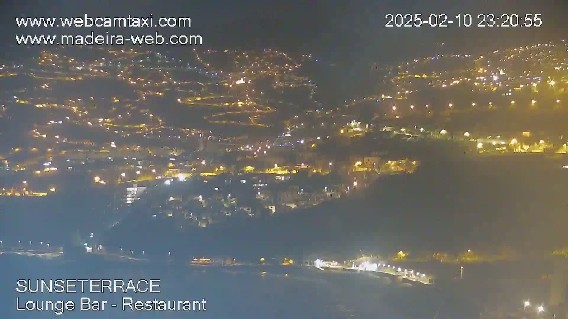 A nighttime, high-angle view of a hillside town illuminated by numerous lights.