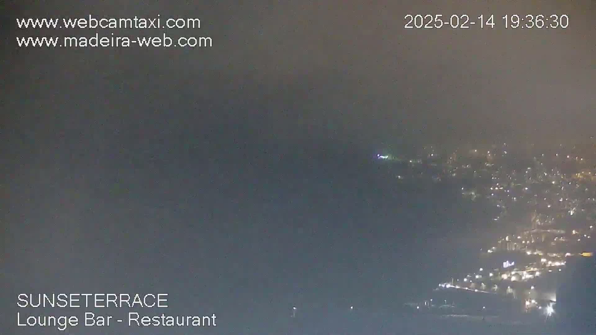 A hazy night scene shows a distant town glowing with lights under a foggy sky.