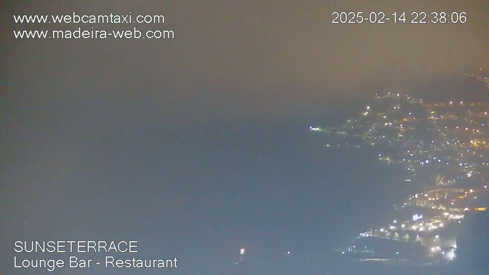 A hazy night scene shows a distant town illuminated with lights below a foggy sky.