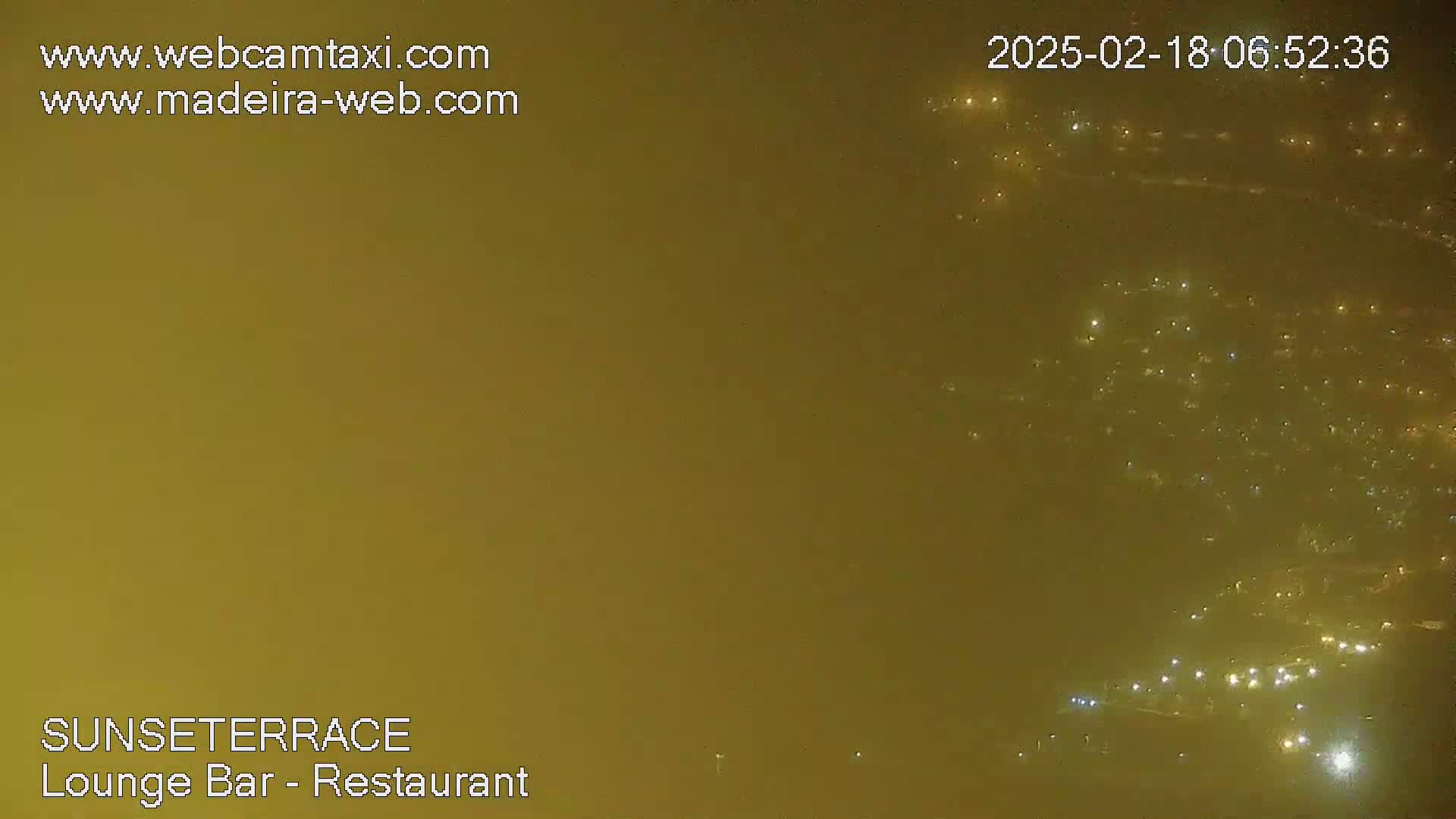 A hazy, nighttime view of a distant city with numerous lights visible through the atmospheric obscuration.