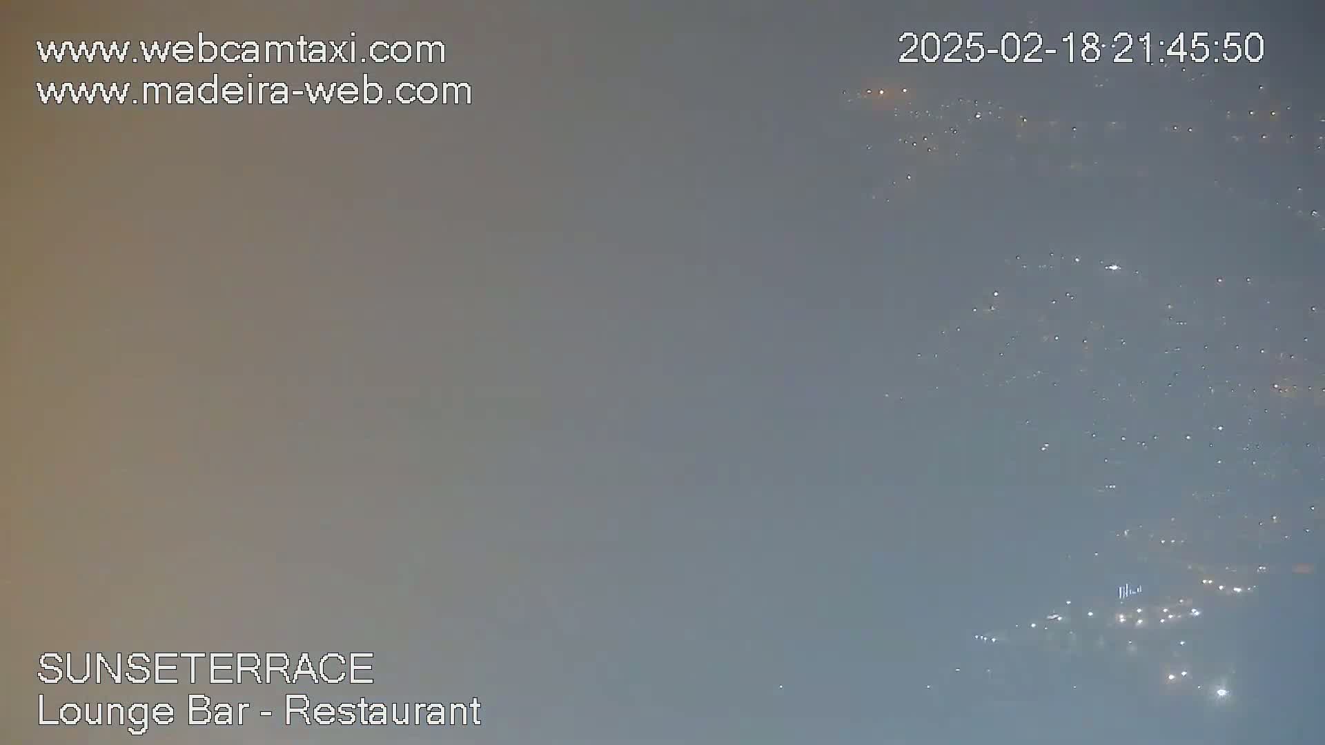 A hazy, dark-grey night sky shows a scattering of distant city lights.